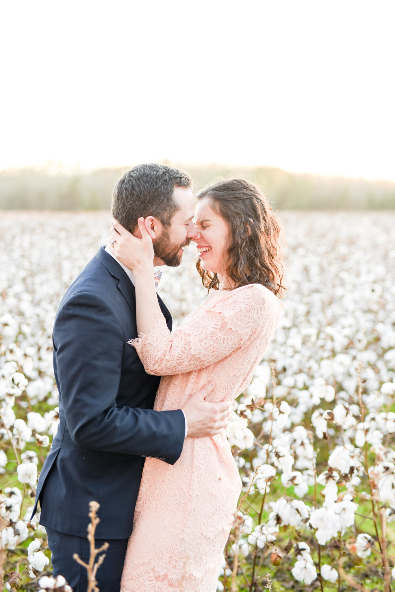 Couple laughs at sunset in cotton field.