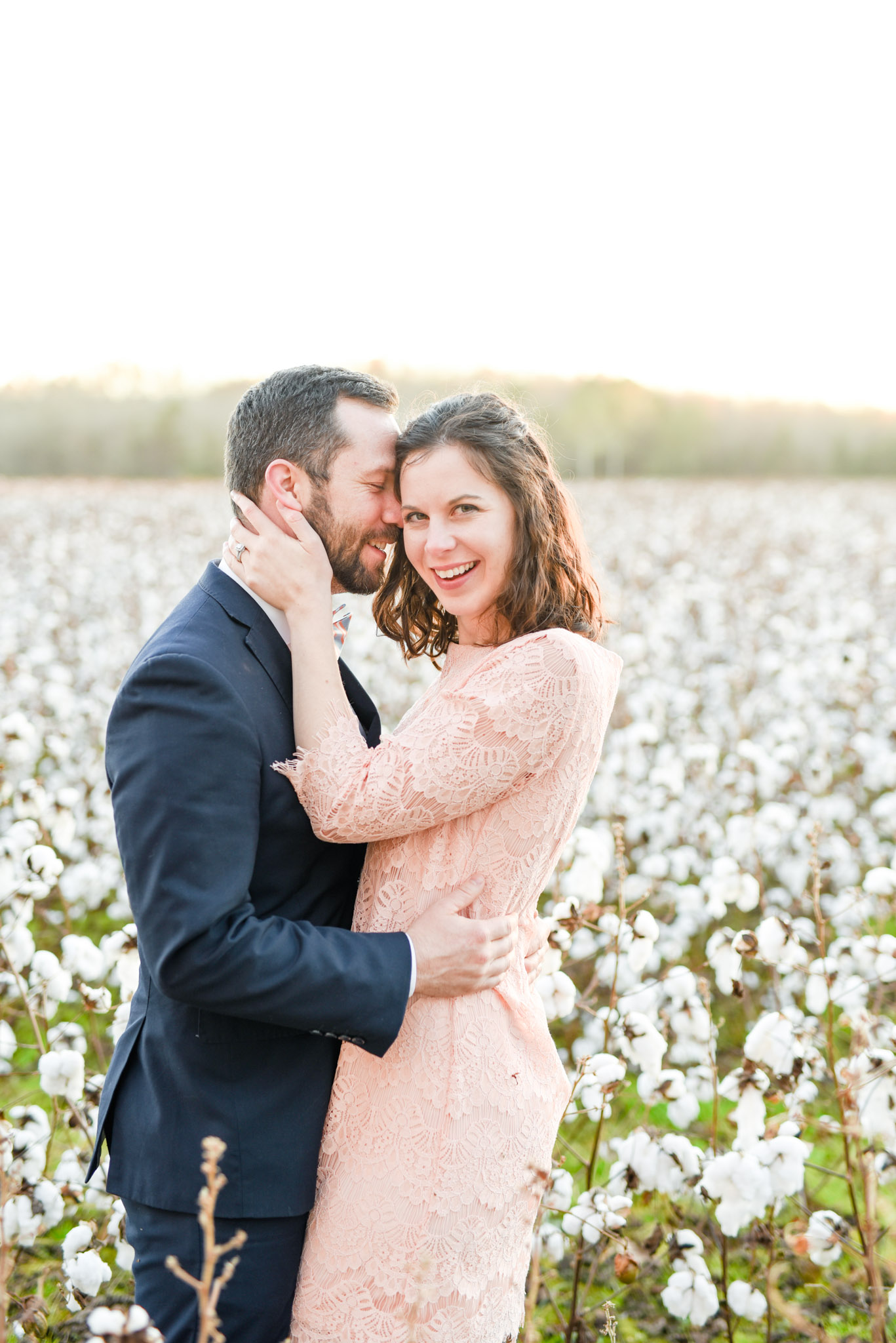 Man and woman laugh in sunset cotton field.