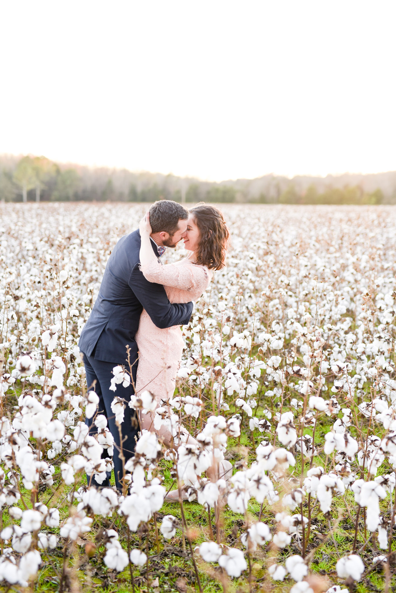 Couple almost kisses while standing in cotton field.