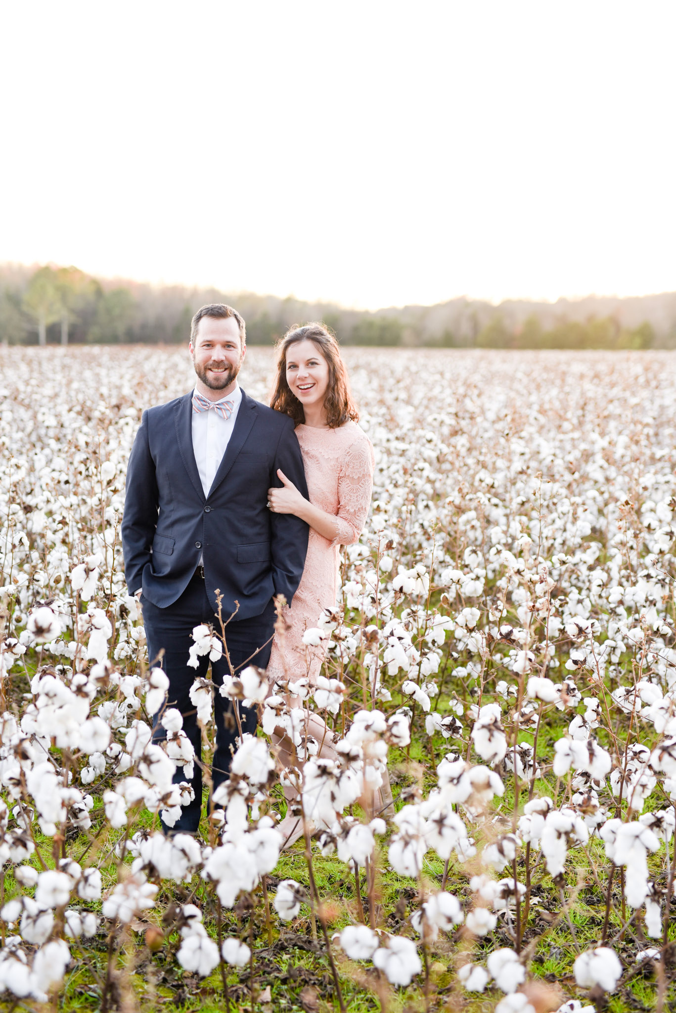 Couple smiles at camera in cotton field.