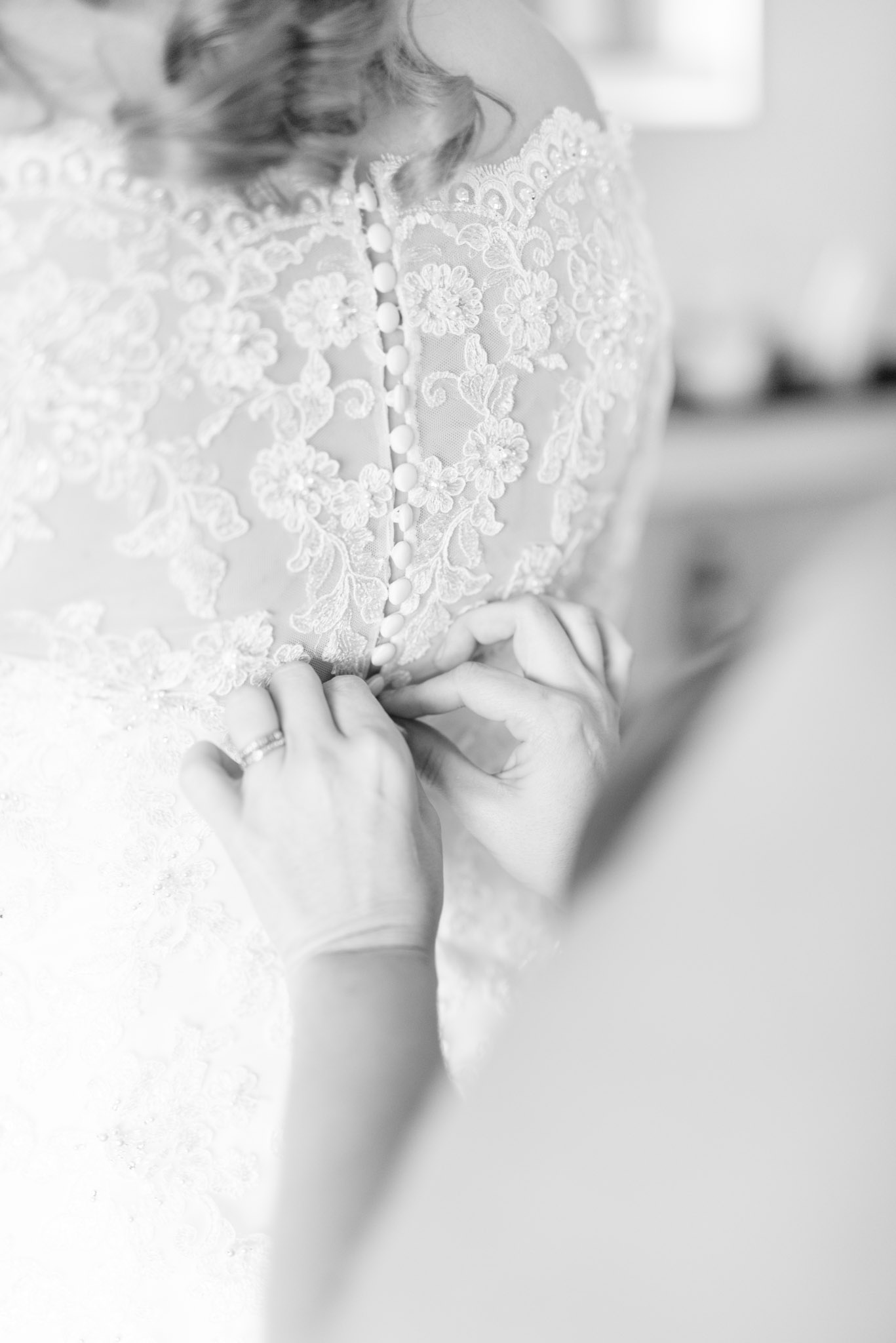 Bridesmaid buttons bride's lace dress.