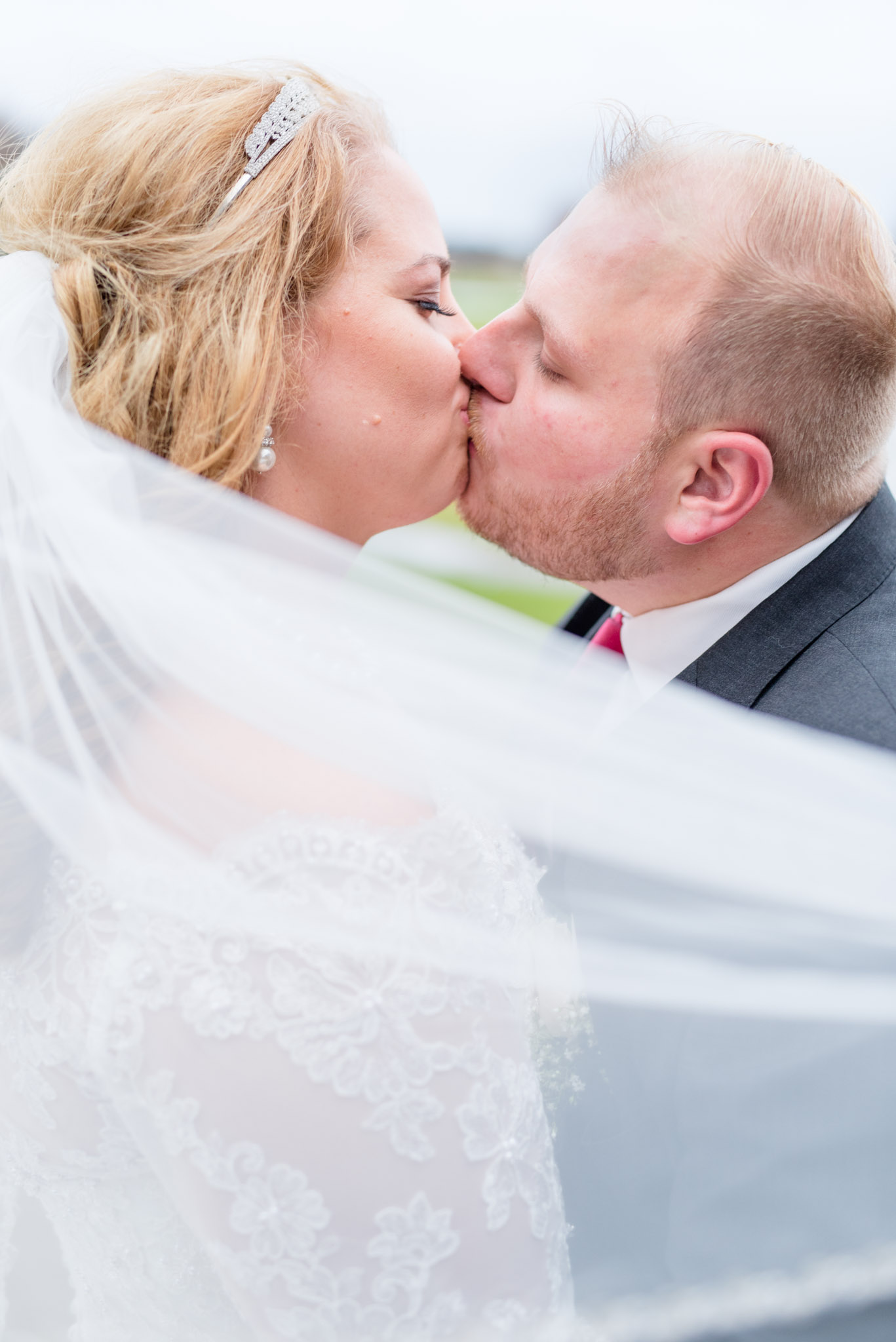 Bride and Groom Kiss while veil blows in wind.