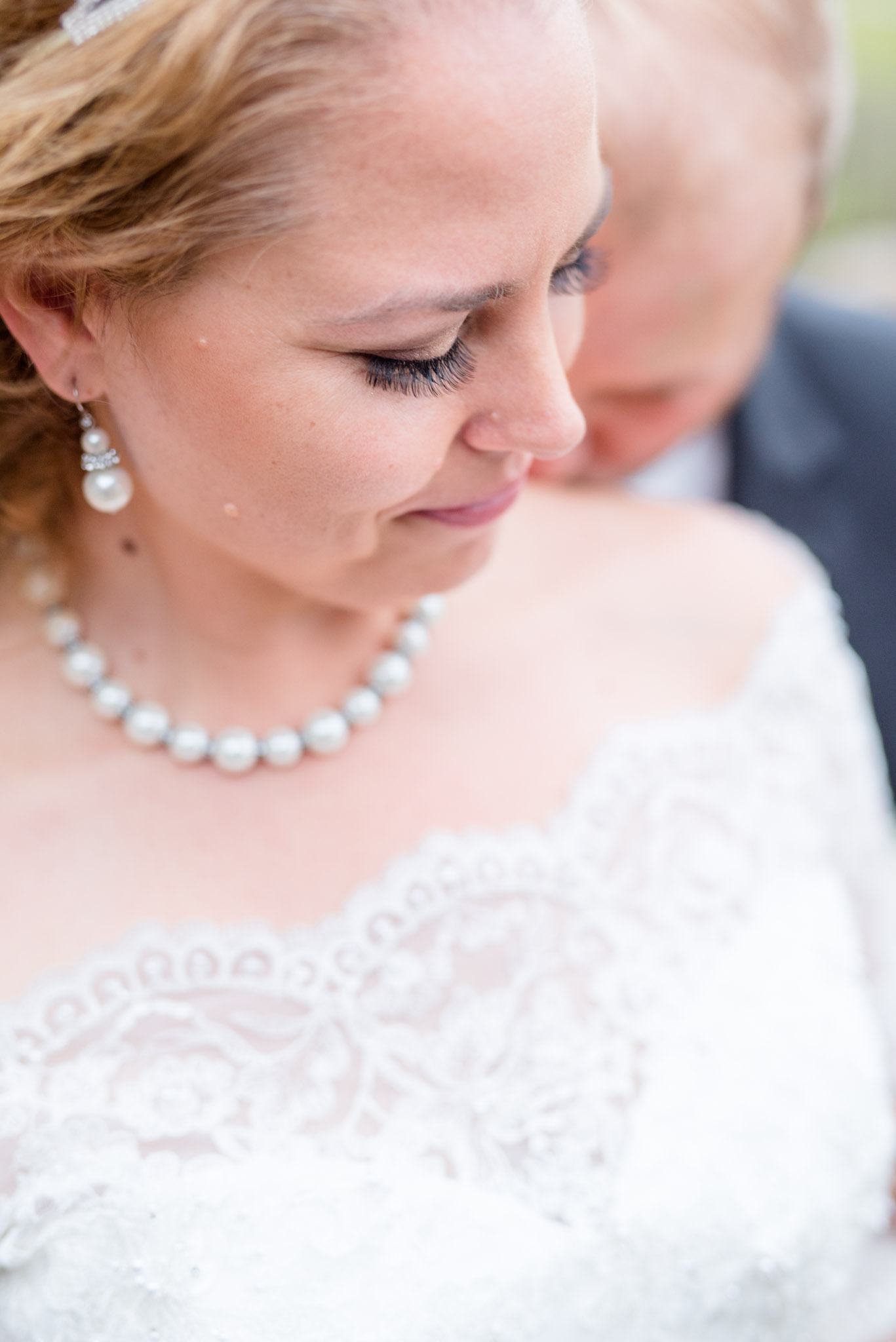 Groom kisses brides shoulder during wedding day.