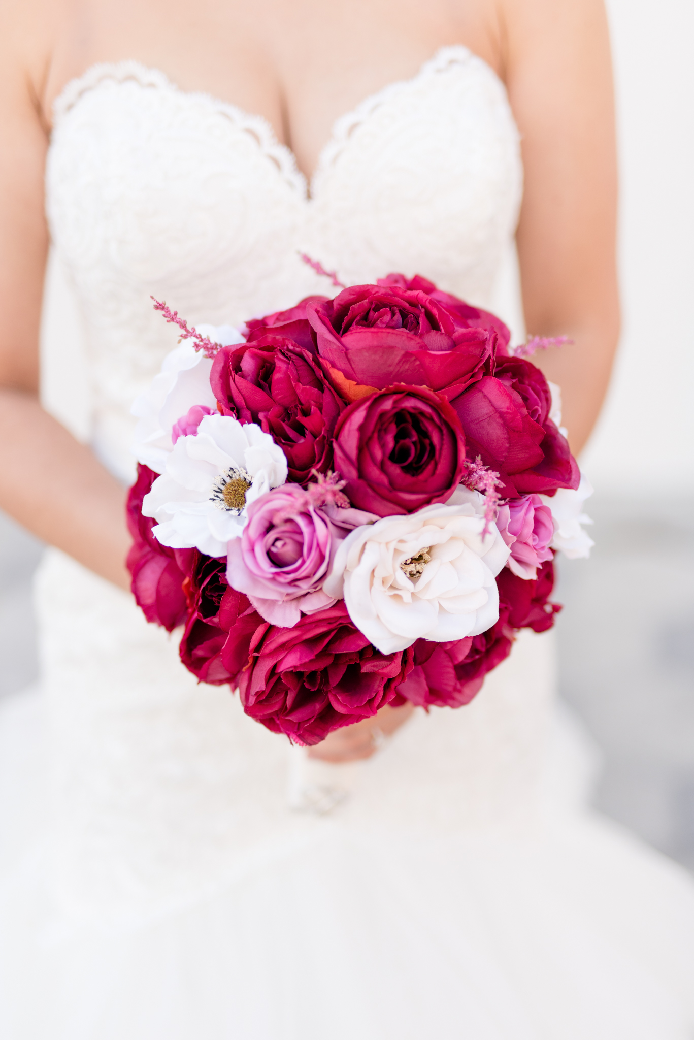 Bridal bouquet of red, pink, and white flowers.