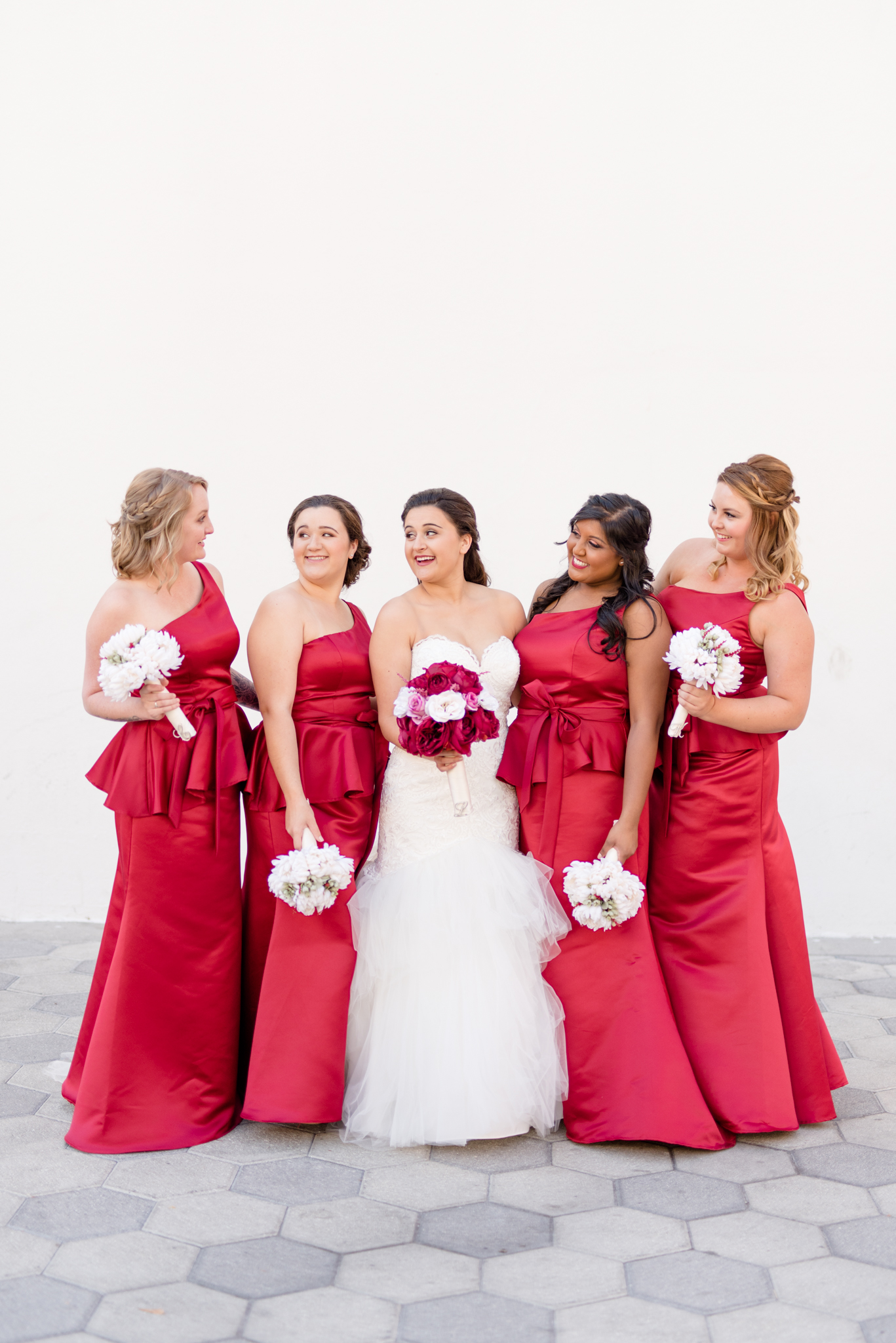 Bridal Party Stands next to white wall and laughs.
