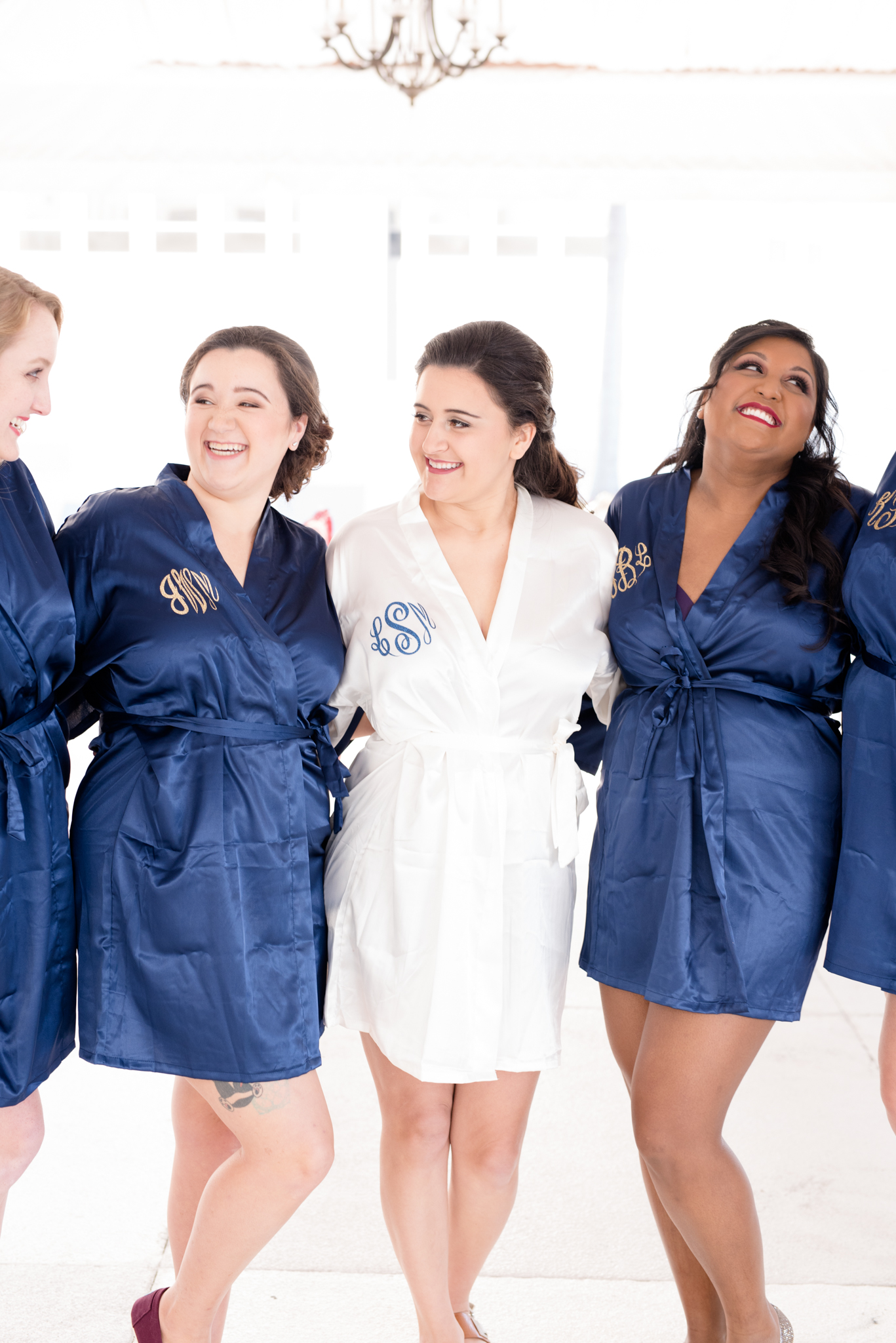 Bridal party laughs while wearing personalized silk robes.