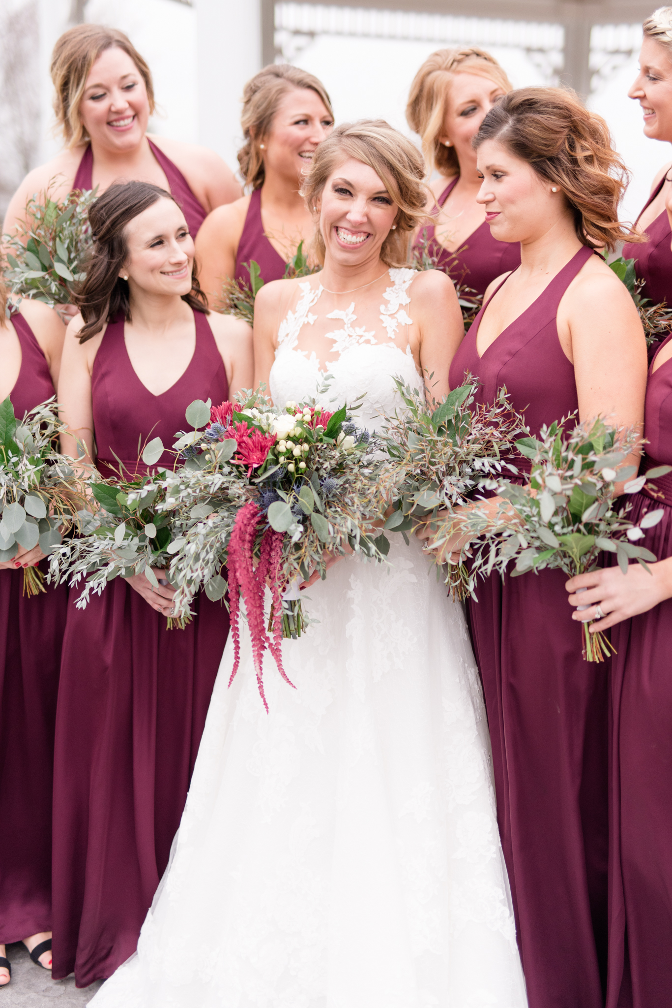 Bride smiles at camera while bridal party laughs.