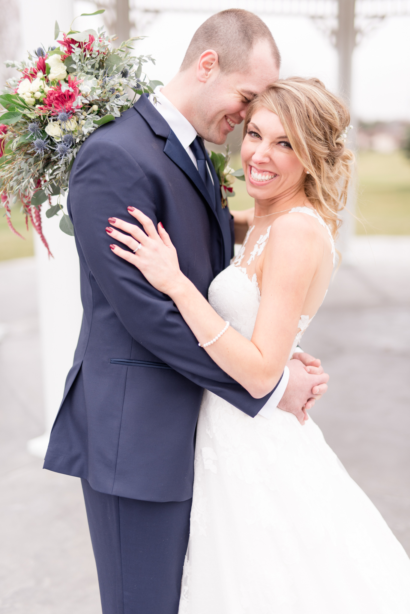 Bride smiles at camera while the groom holds her.