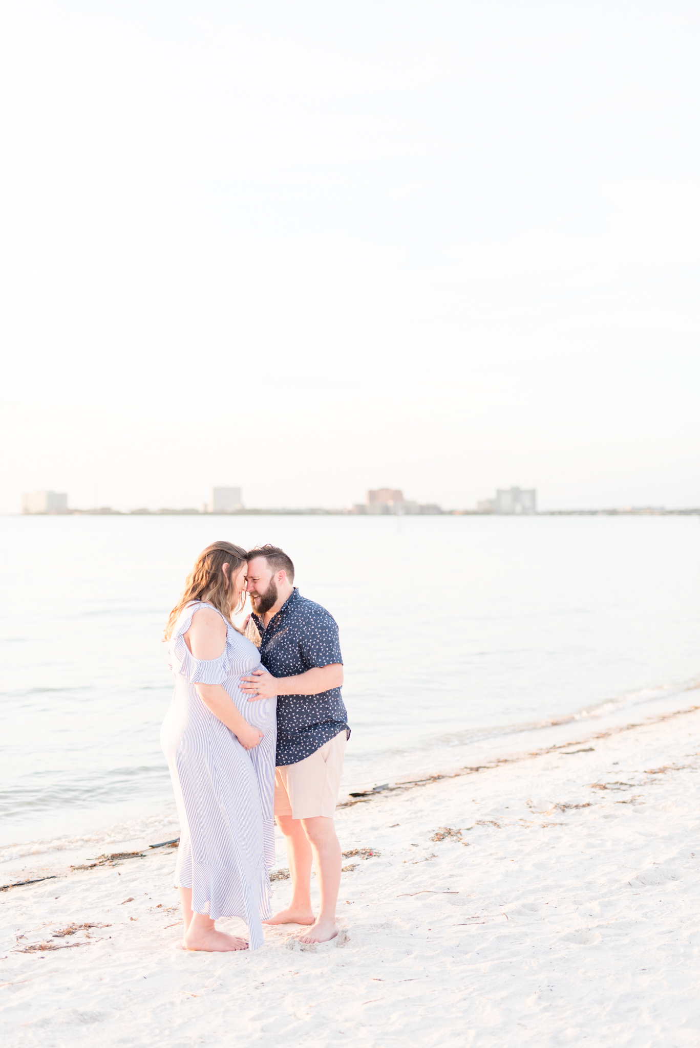 Tampa couple cuddles on beach during maternity session.