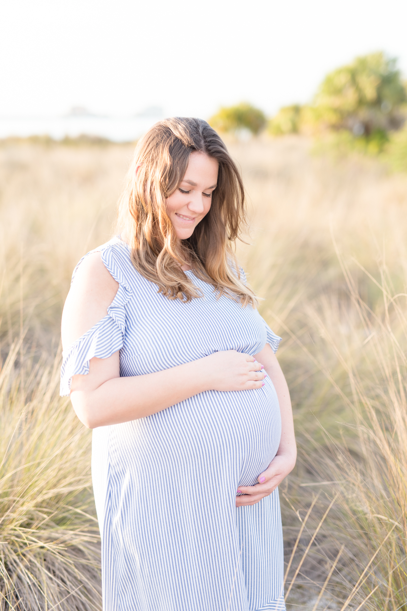 Expecting mother looks down and smiles in Tampa.