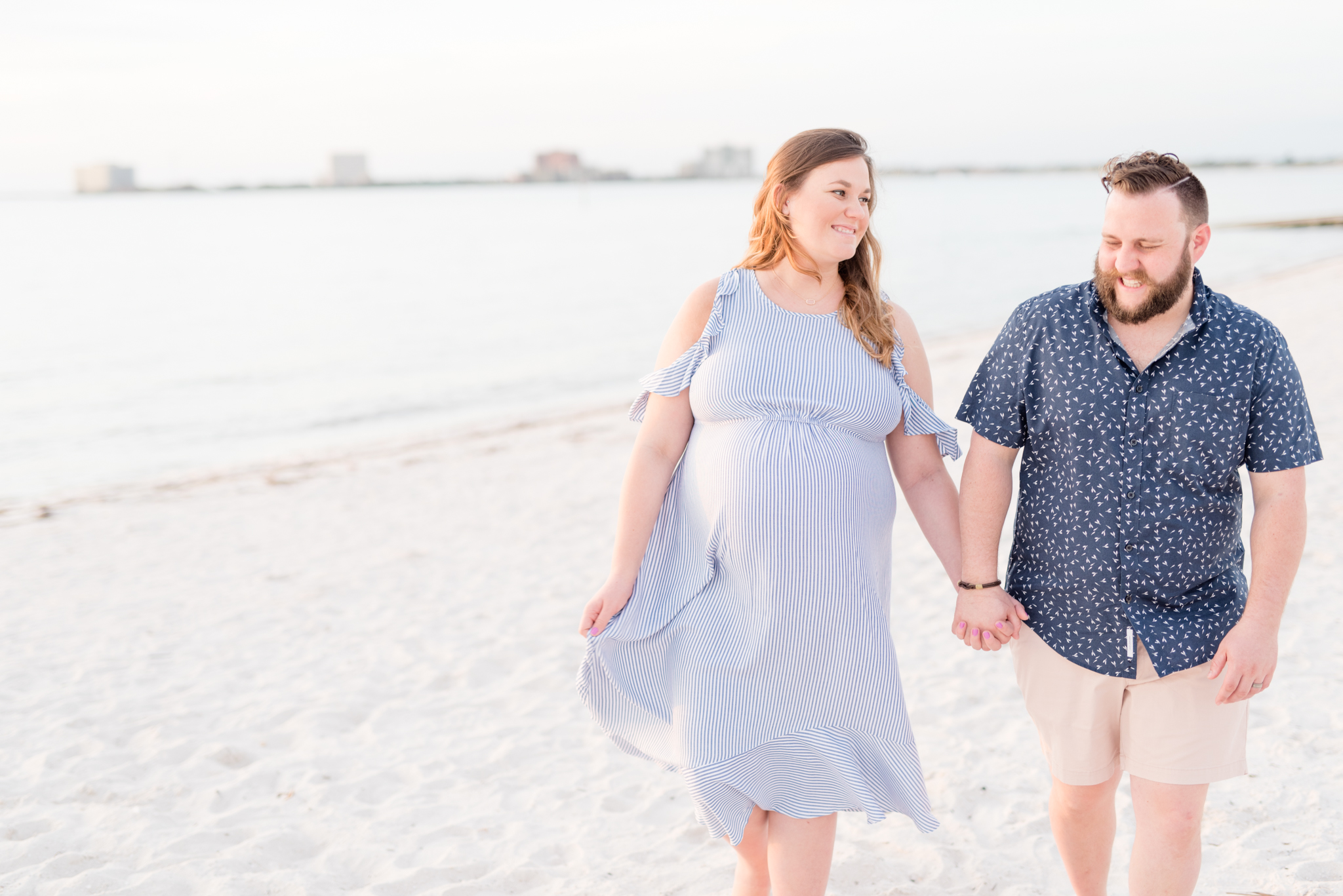 Expecting couple walks along Tampa beach.