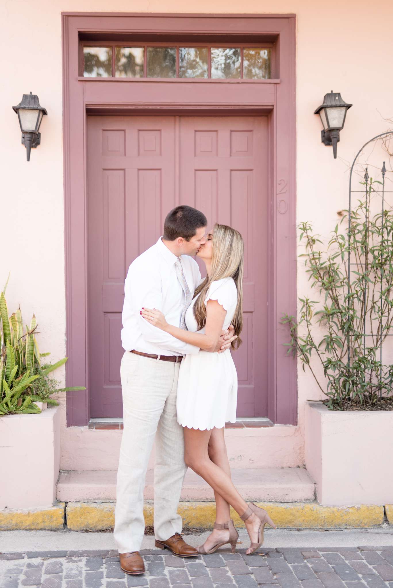 Married couple kisses in front of purple door.