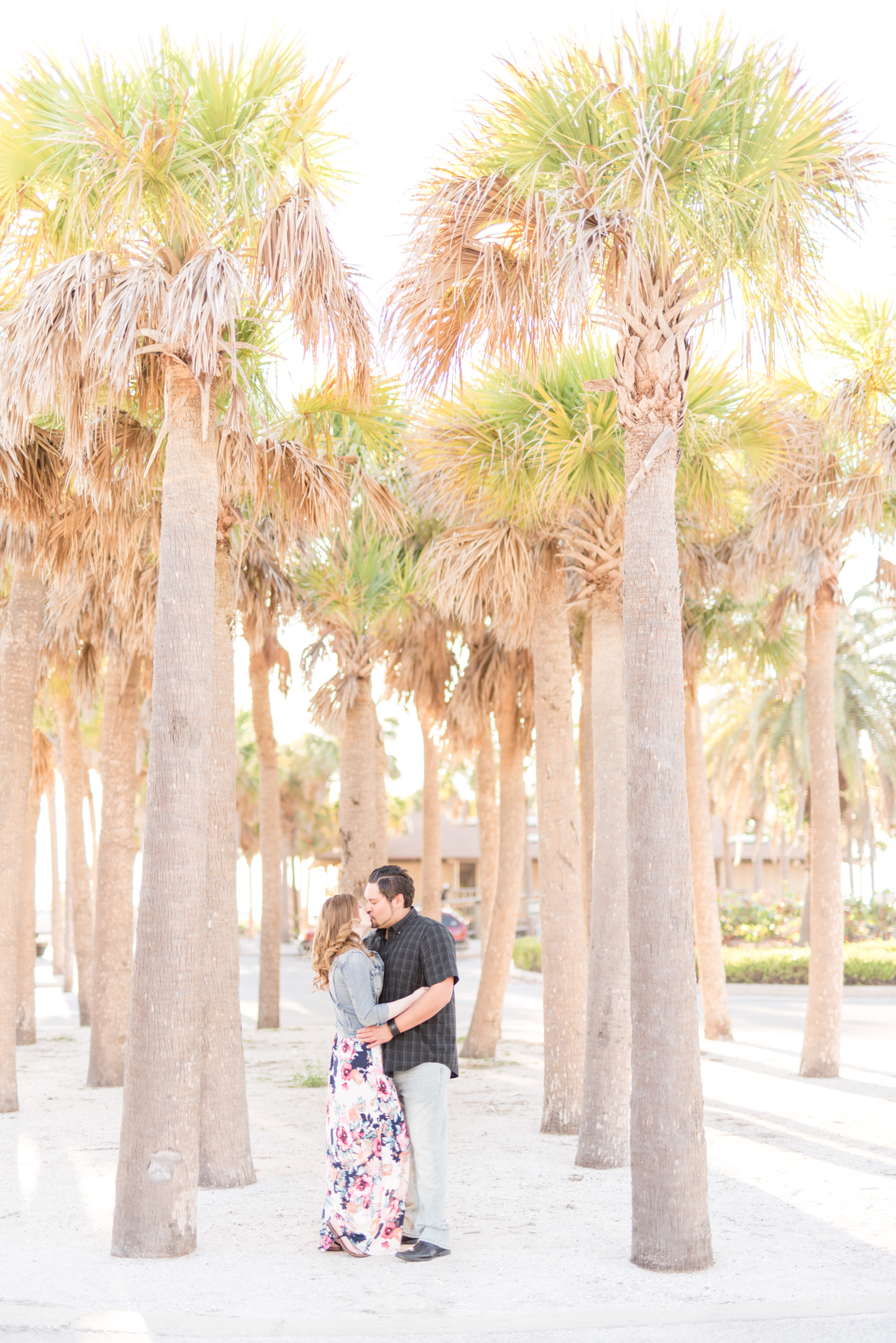 Couple kisses while surrounded by palm trees.
