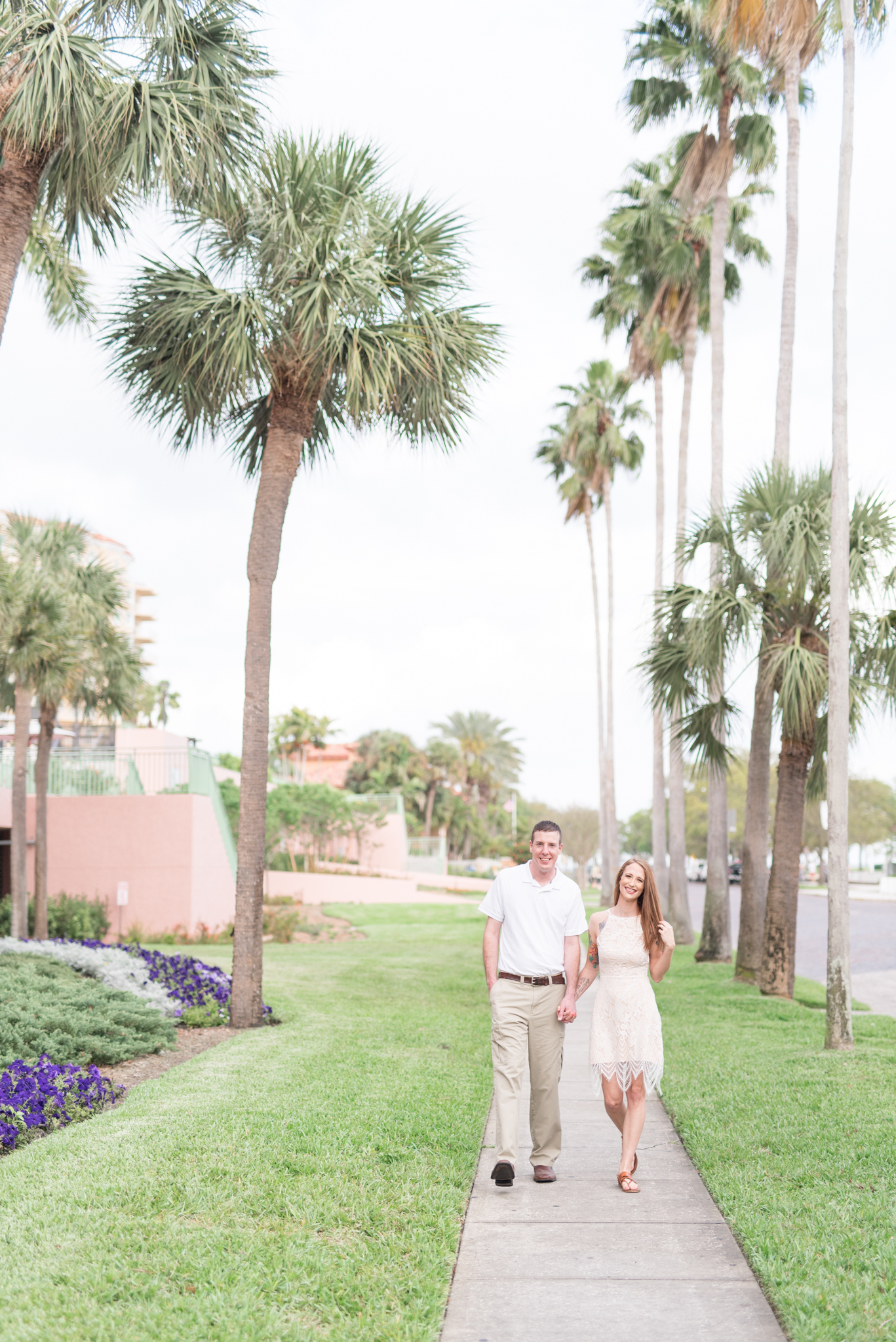 Man and woman walk in between palm trees.