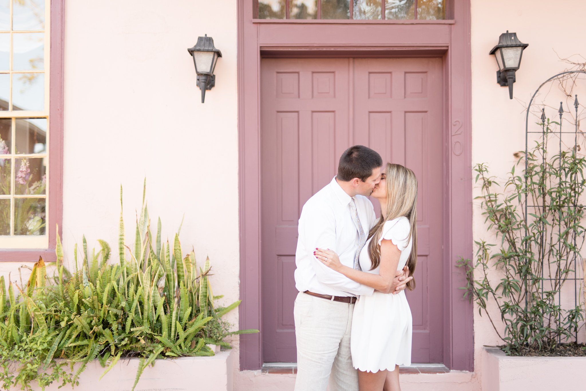 Couple kisses in front of purple door.