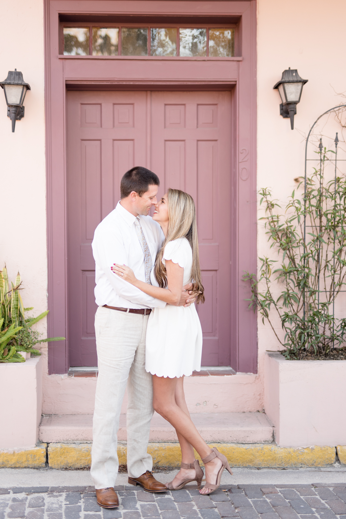 Man and woman almost kiss in front of purple door.