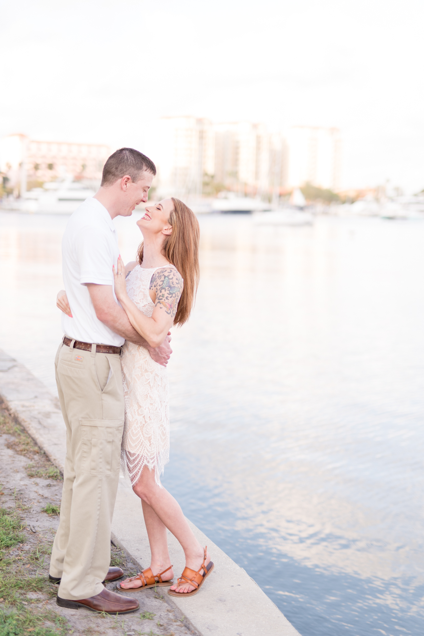 Engaged couple smiles next to water in St. Petersburg, Florida.