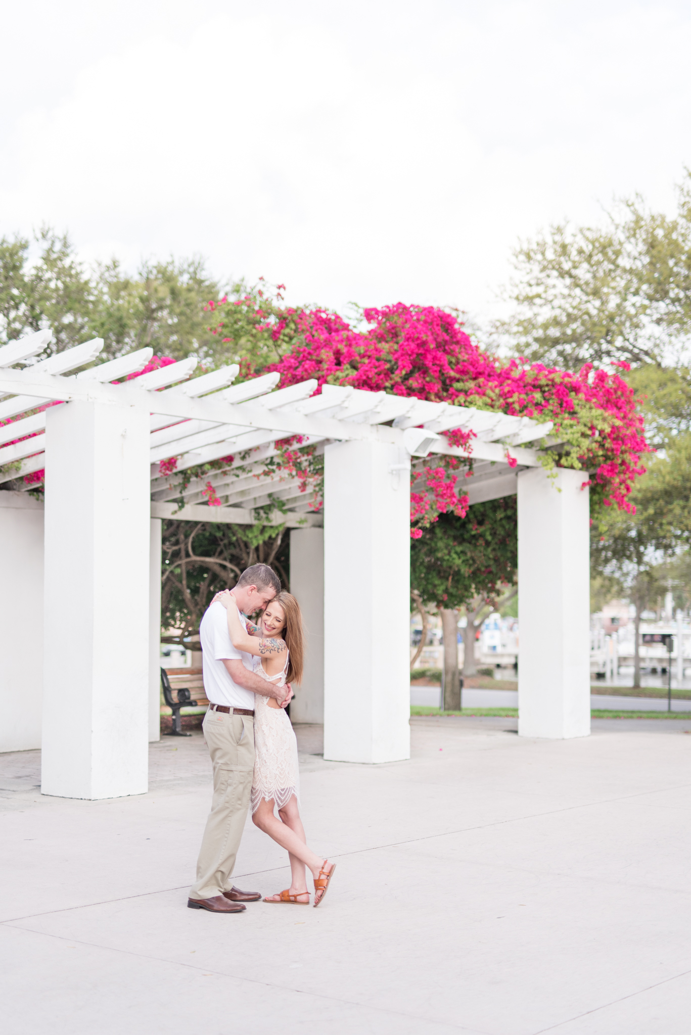 Engaged couple stand under arbor at North Straub Park.