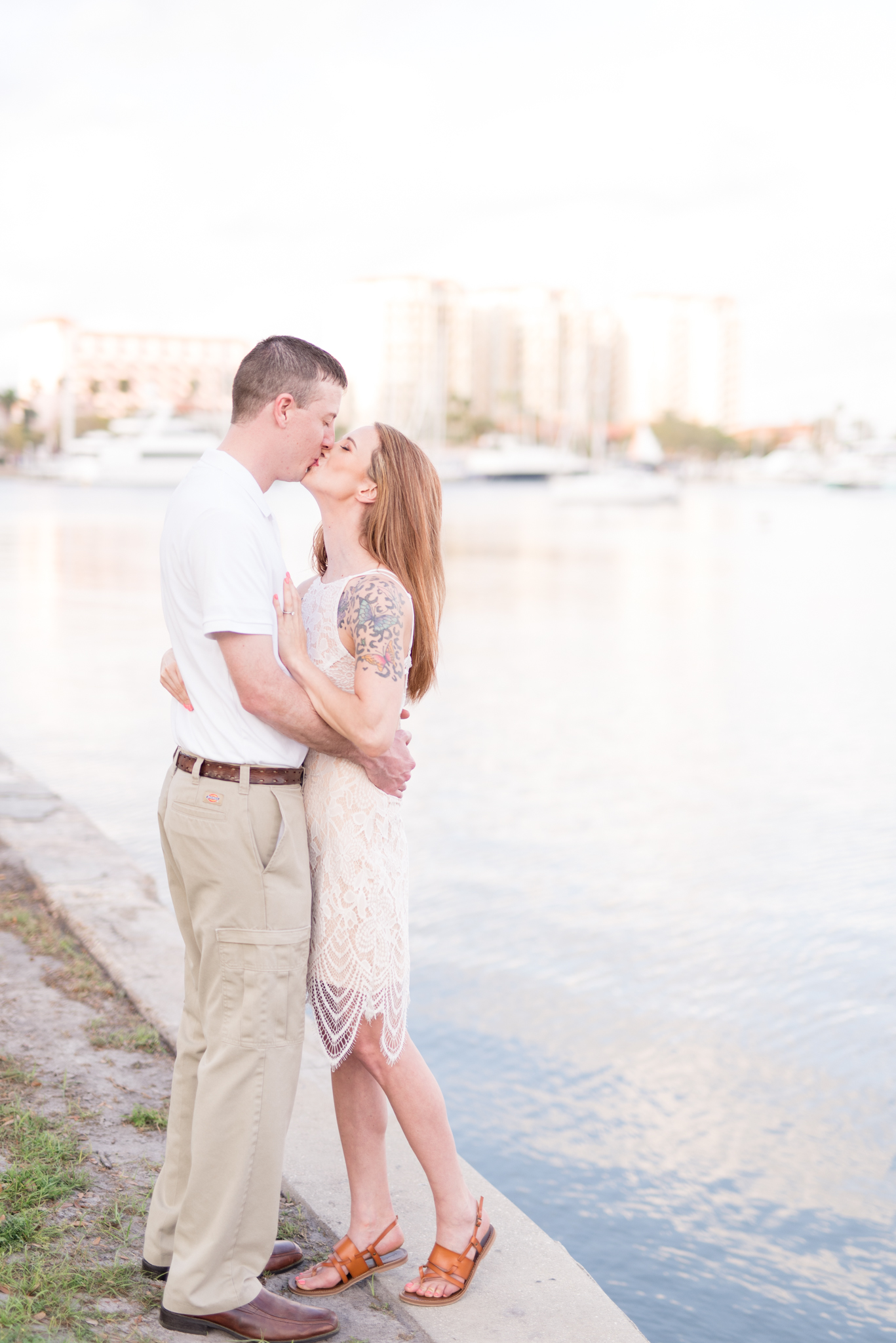 Engaged couple kiss next to water in St. Petersburg, Florida.