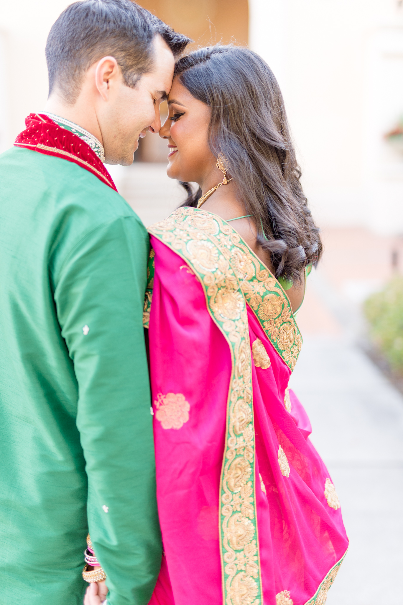 Man and woman smile in traditional Indian outfits.