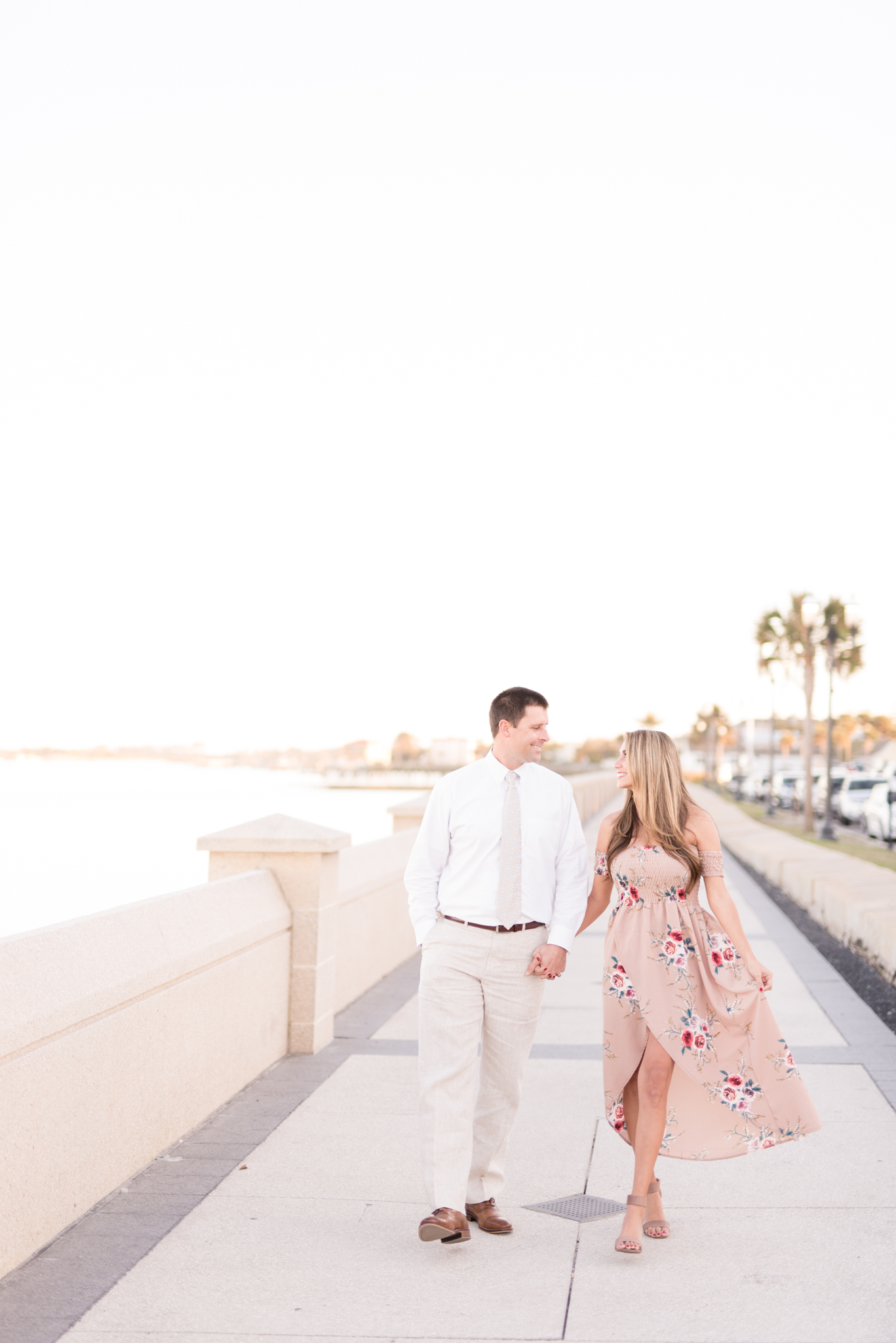 Couple walks and smiles at each other by the ocean.