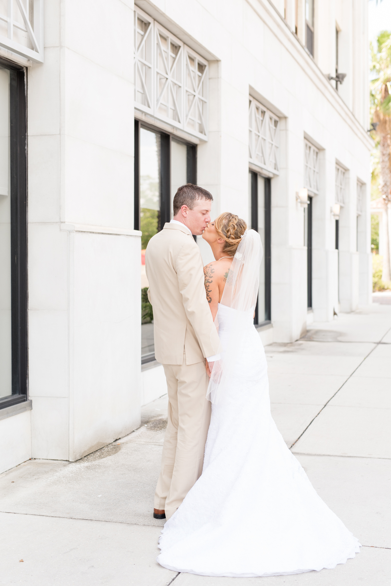 Bride and groom kiss on downtown street.