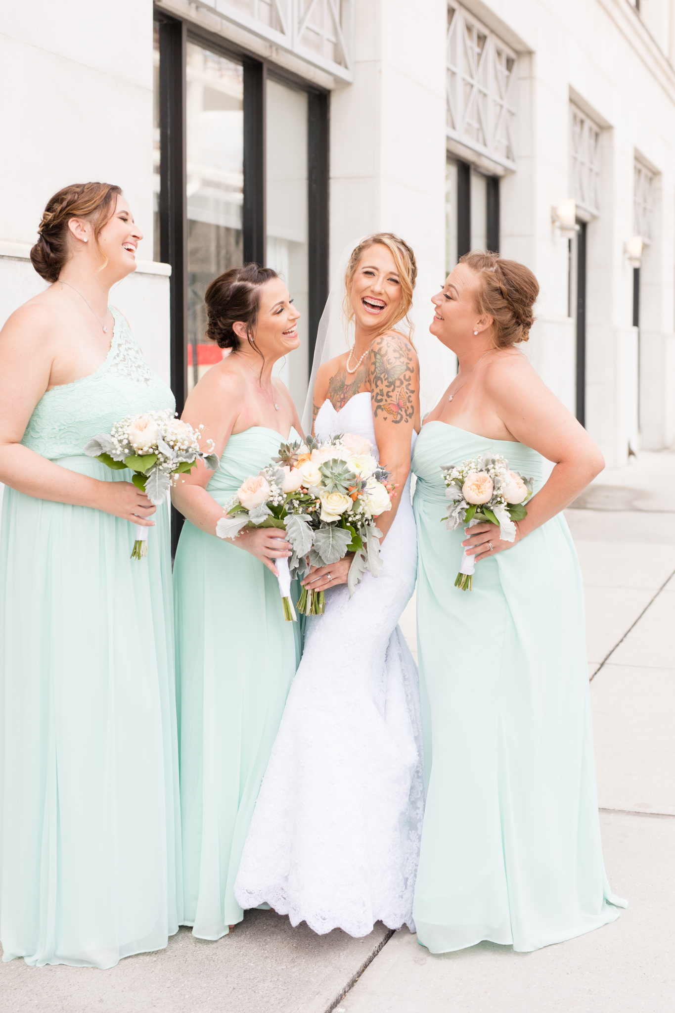 Bride laughs towards camera with bridesmaids.