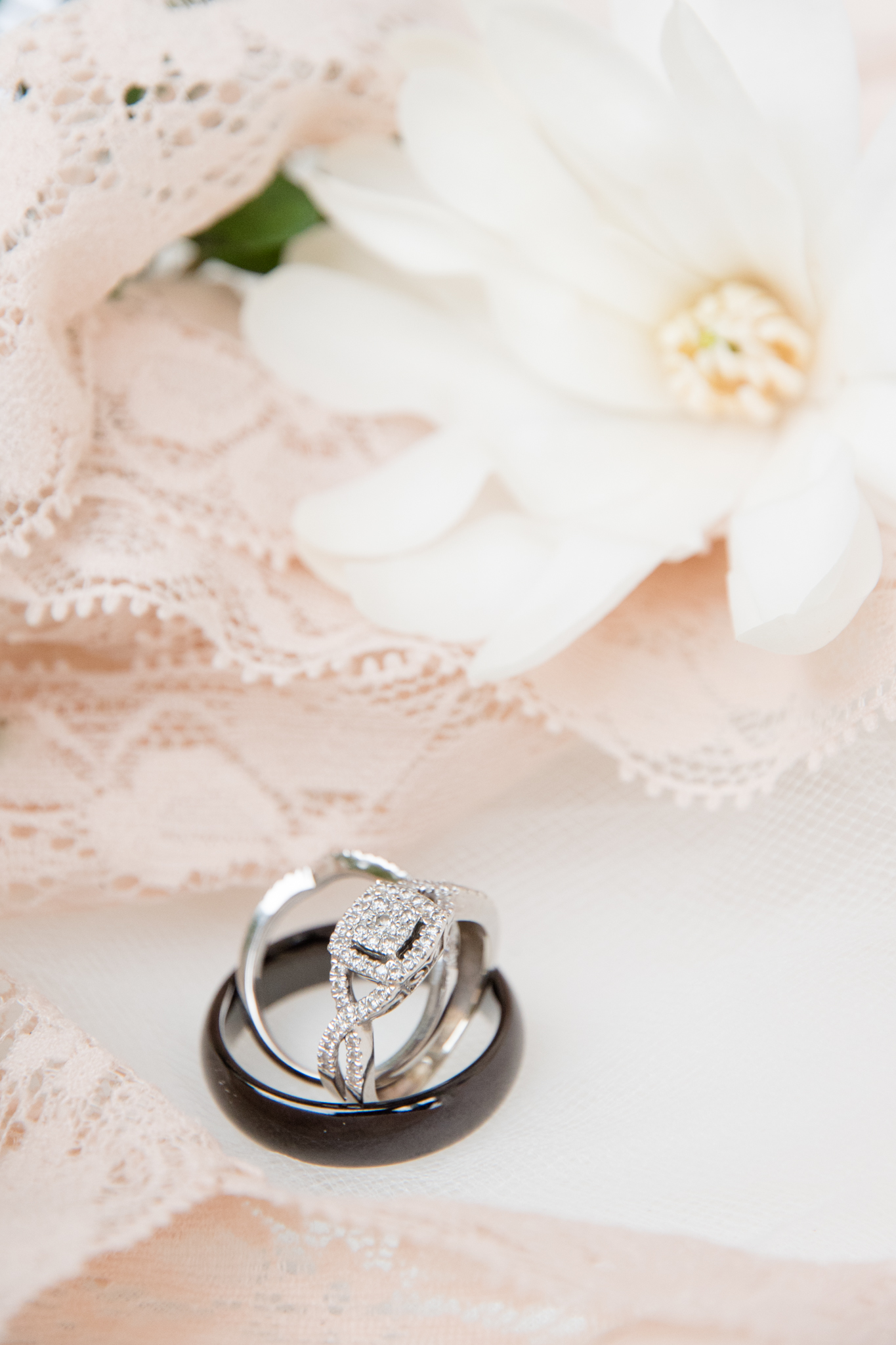 Wedding rings stacks next to flowers and lace