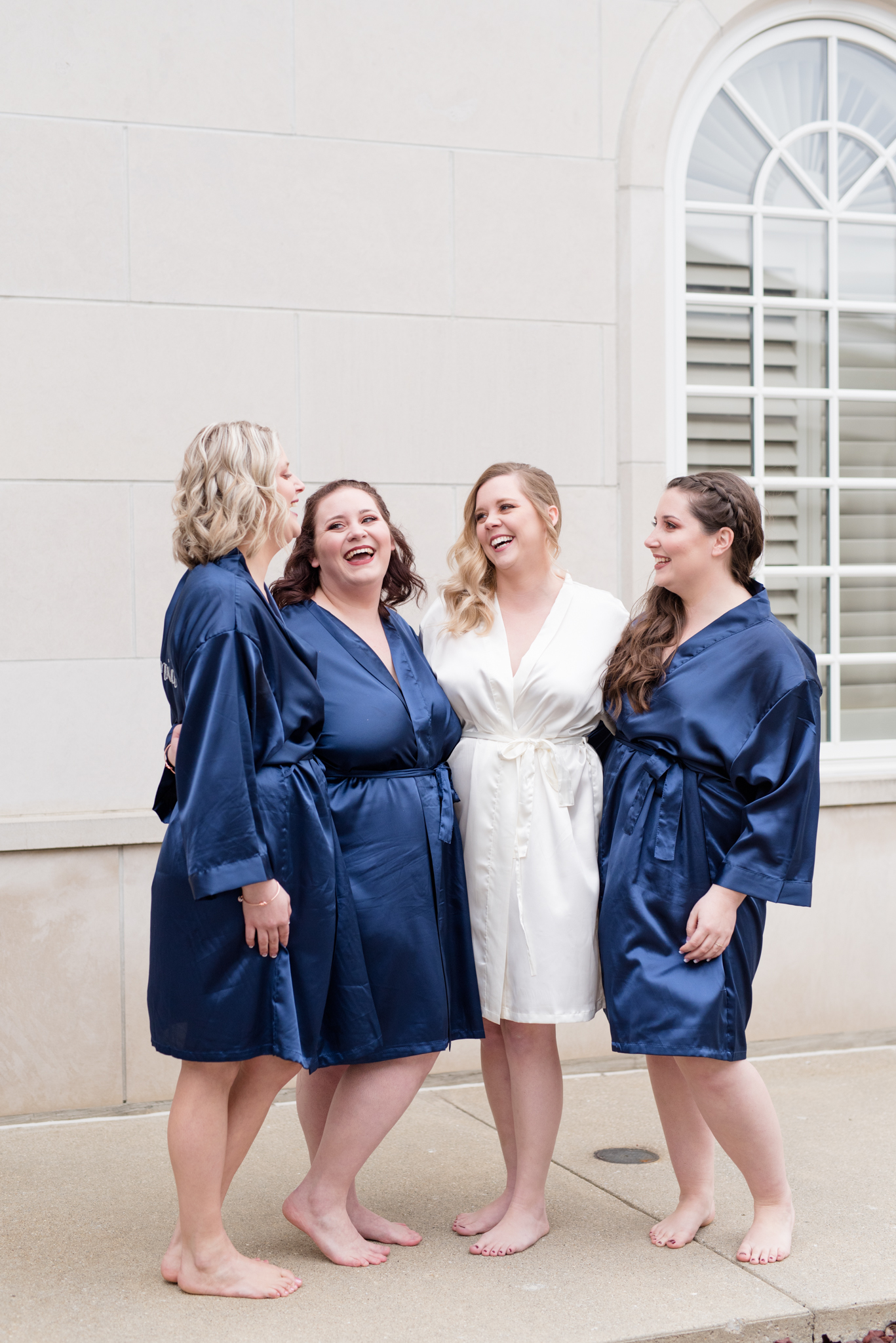 Bride and bridemaids laugh in robes
