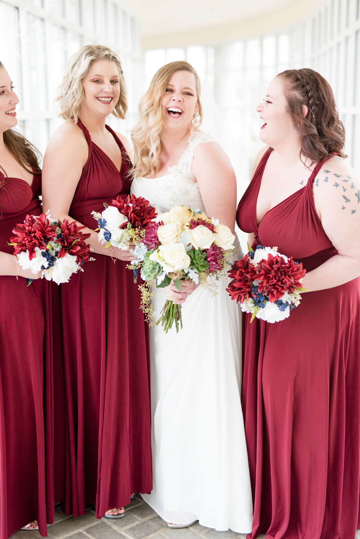 Bride laughs surrounded by bridesmaids.