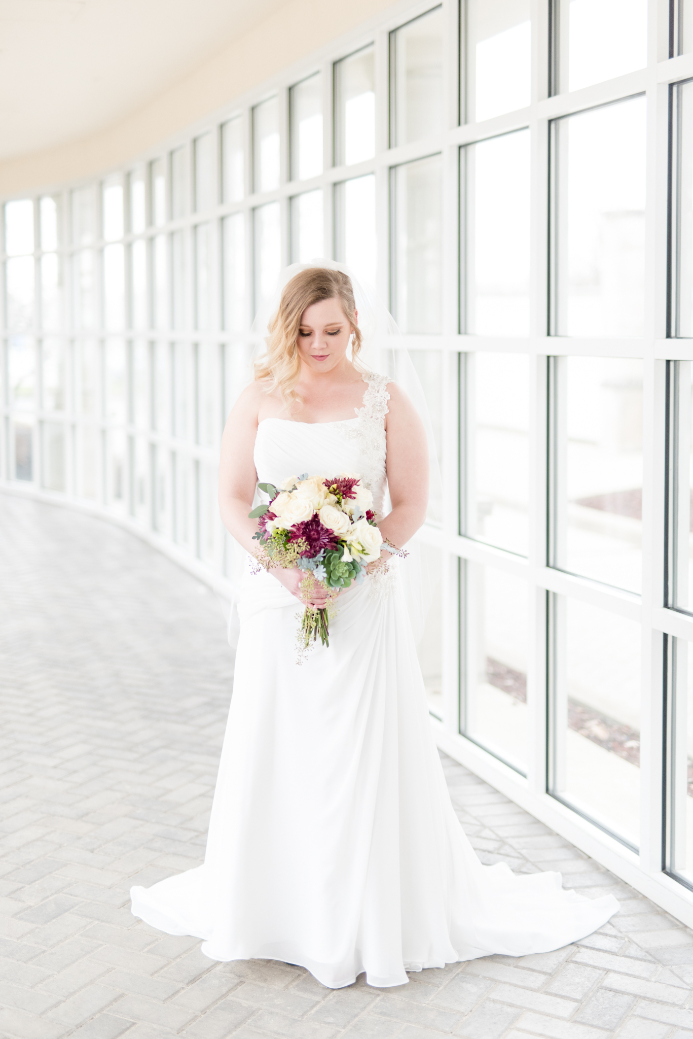 Bride looks down at bouquet.