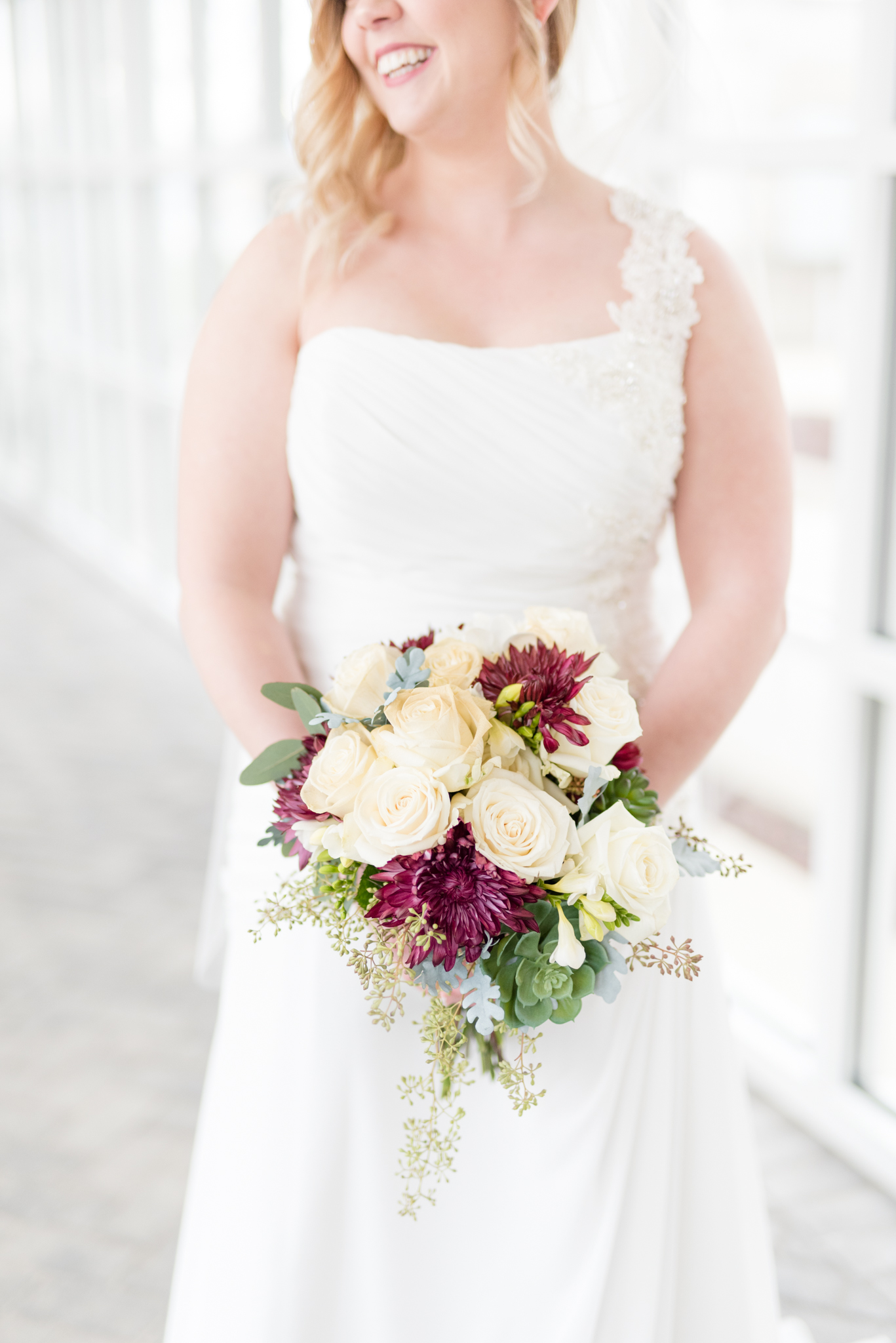 Bride holds bouquet and smiles.