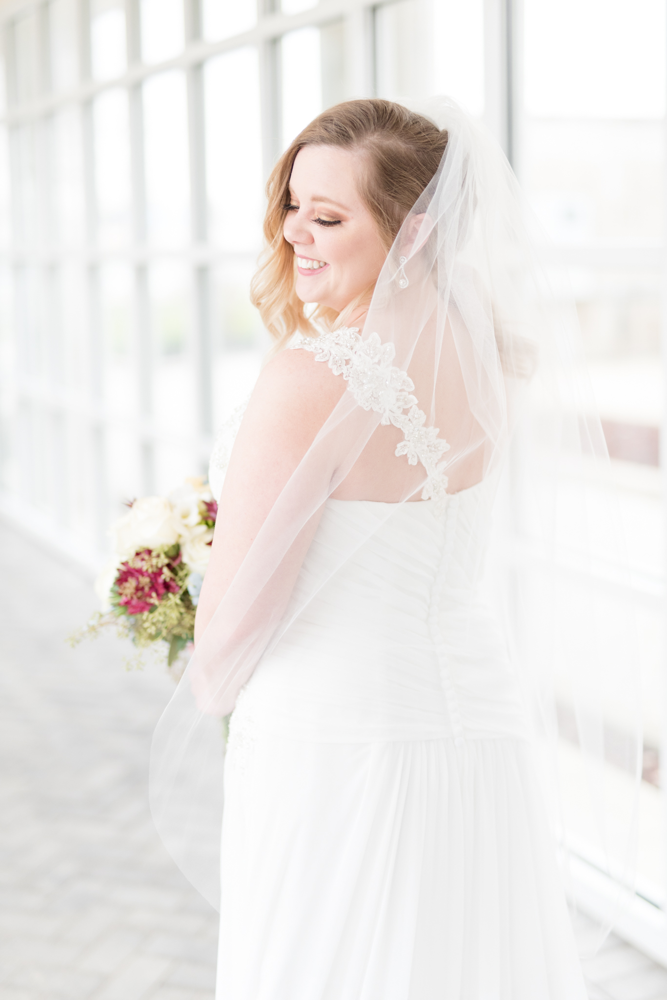 Bride looks over shoulder and smiles.