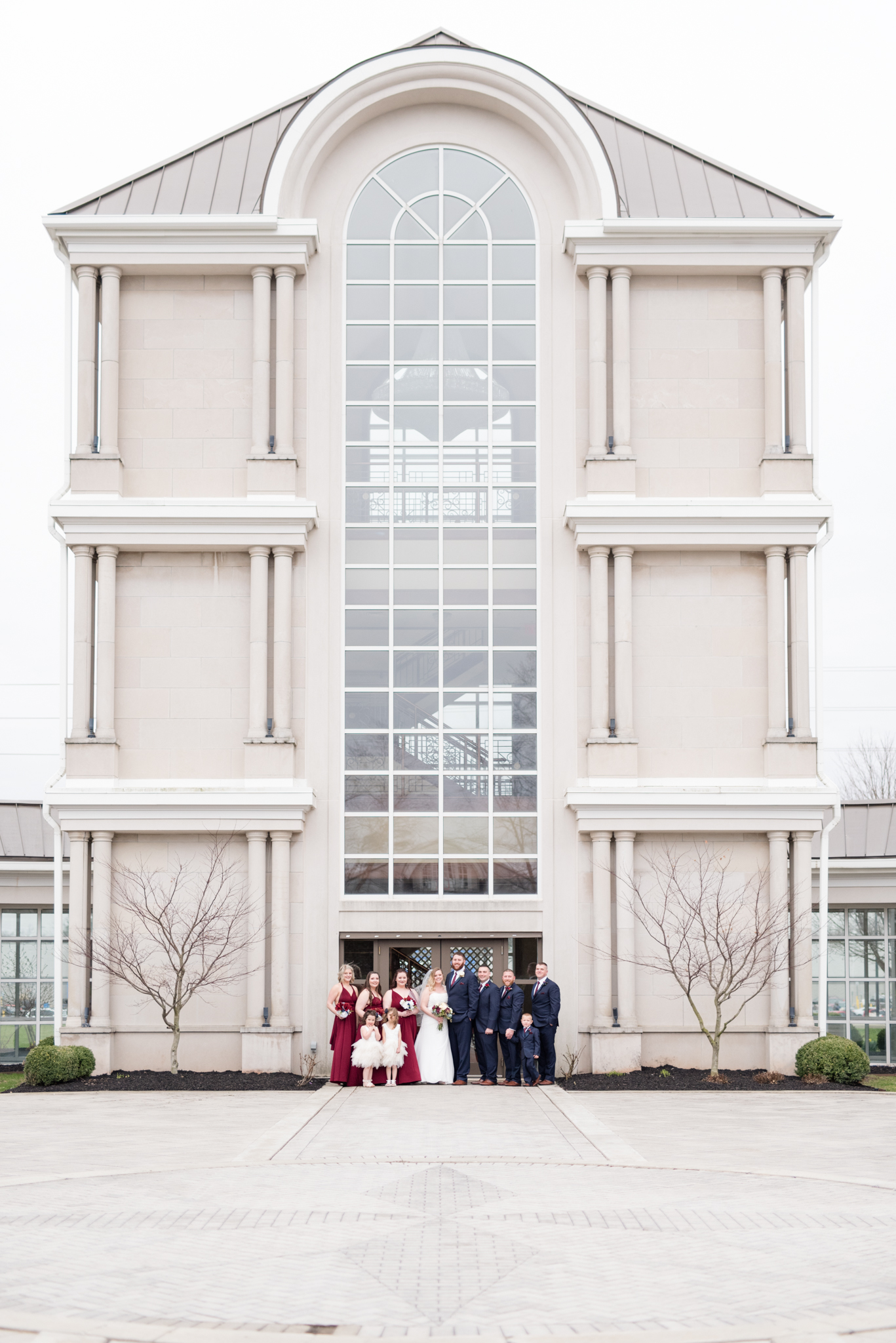 Bridal party stands by large building.