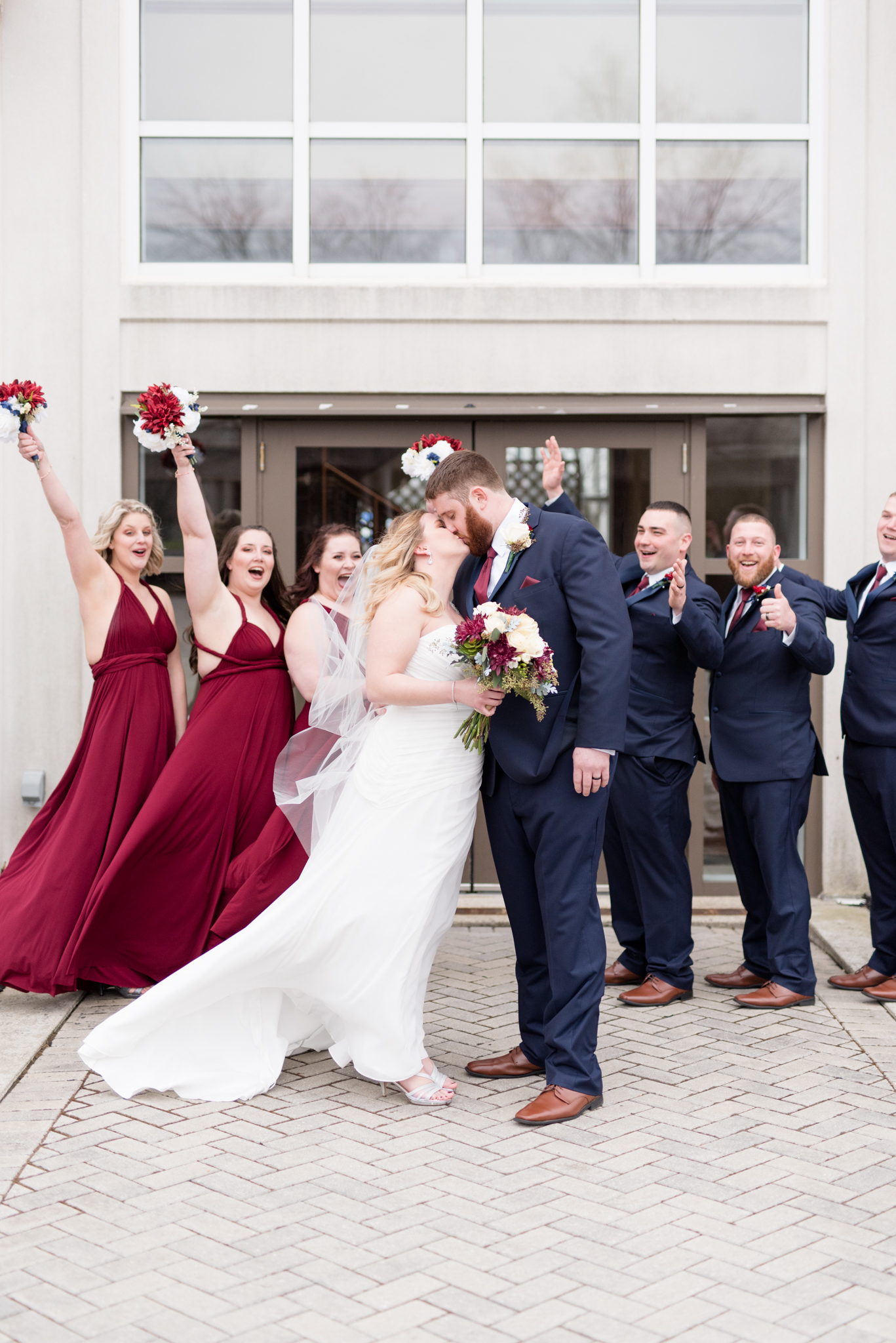 Bride and groom kiss whille wedding party cheers.