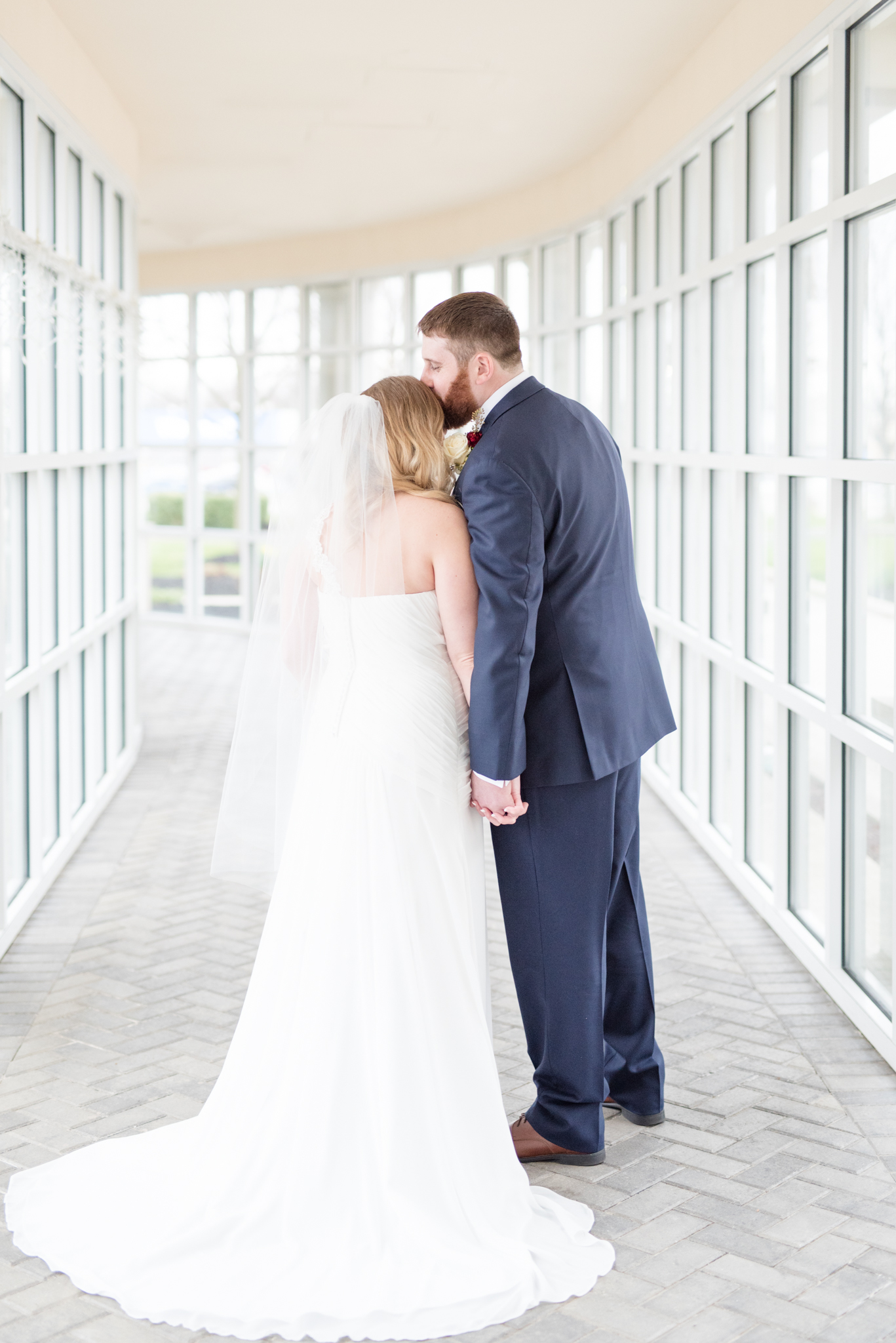 Groom kisses bride's forehead.