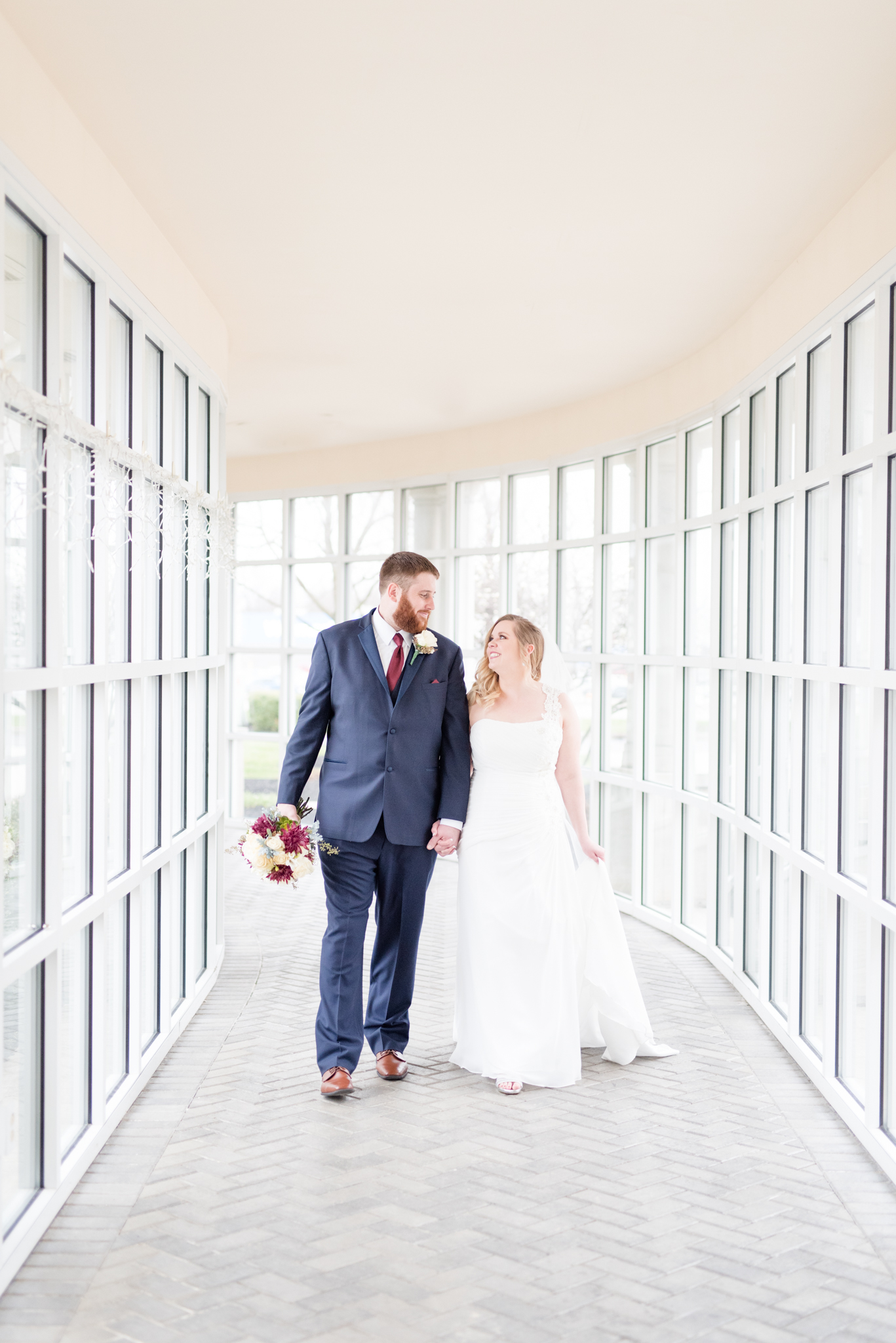 Bride and groom walk down hallway together.