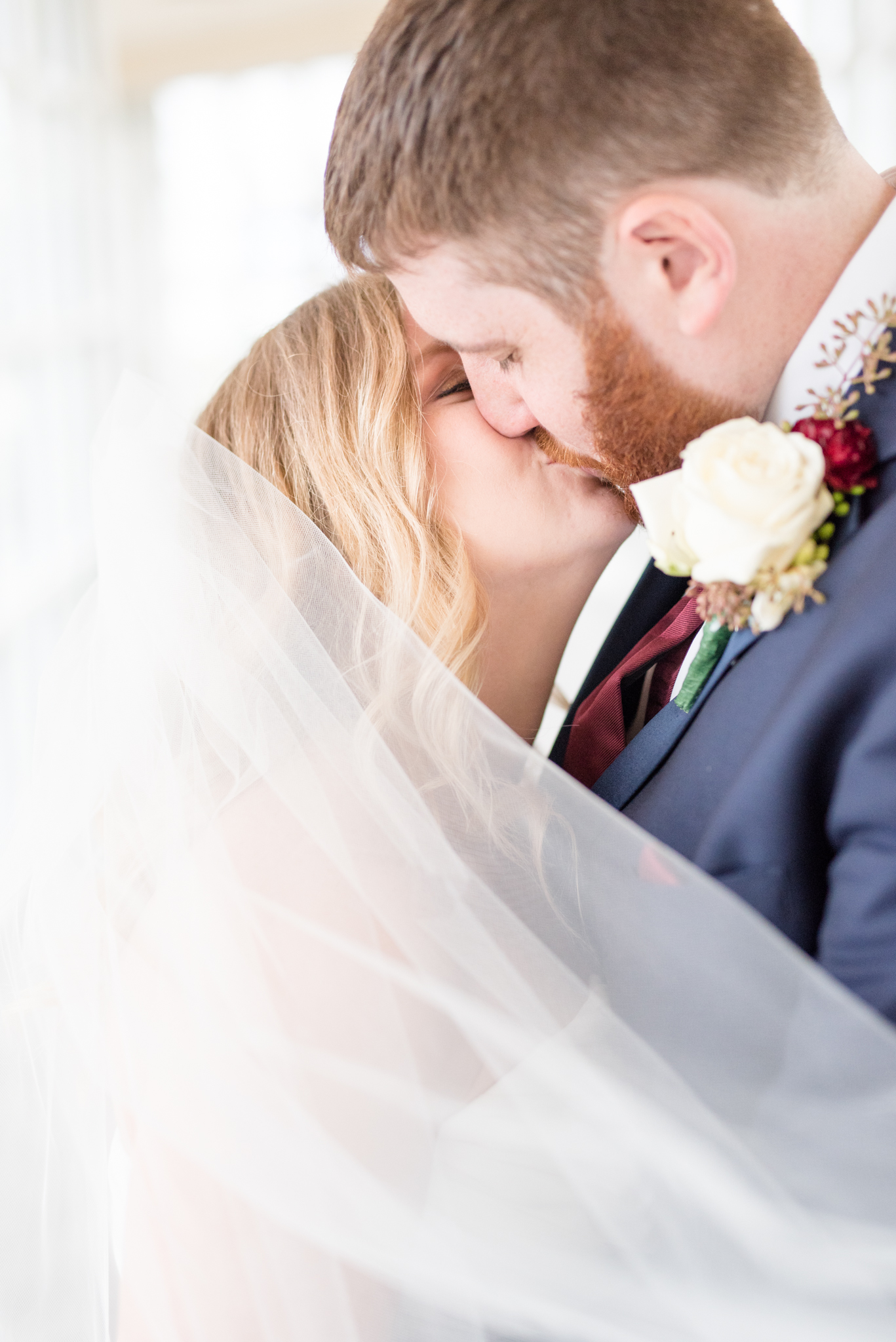 Bride and groom kiss with veil blowing.