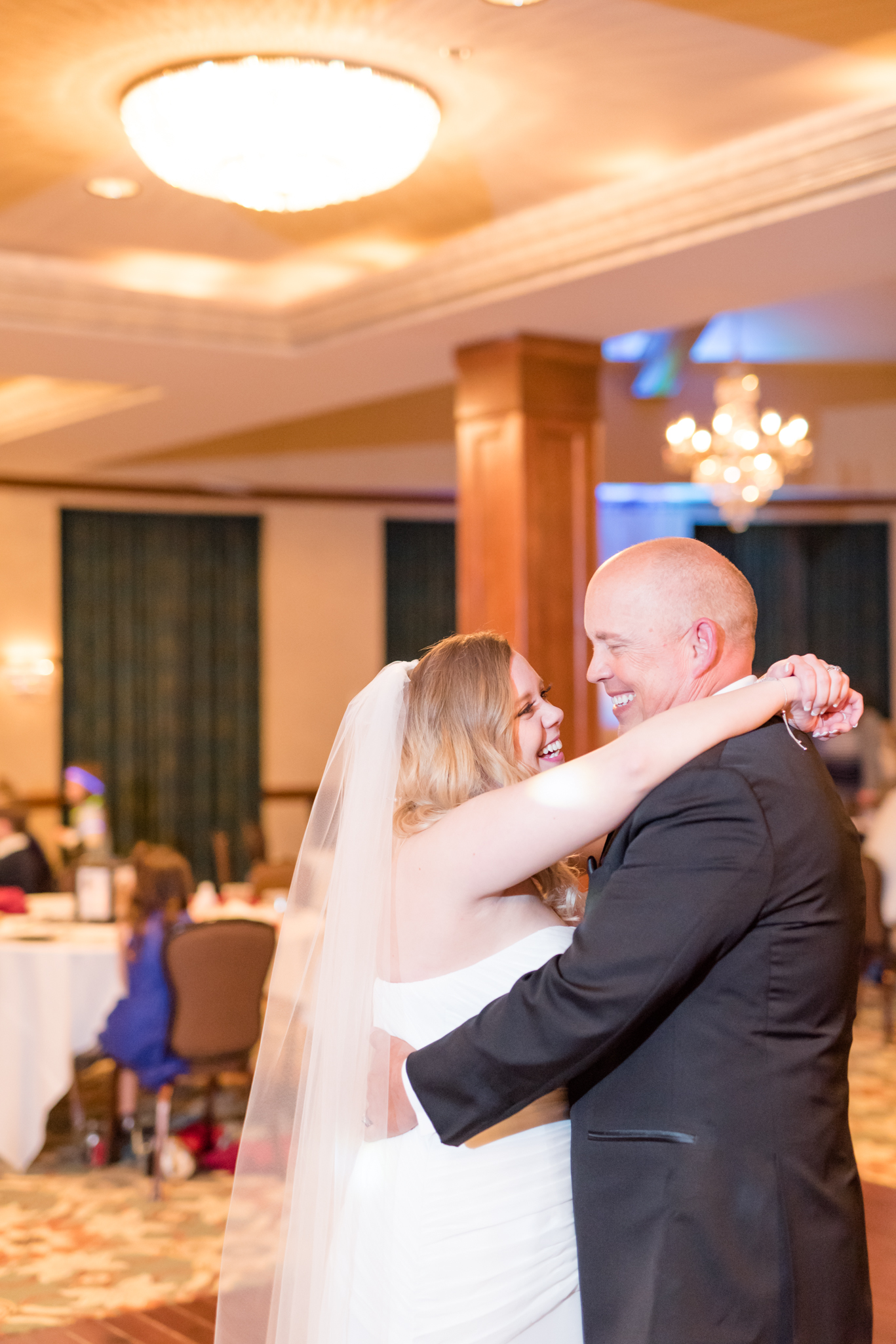 Bride and father laugh during dance.