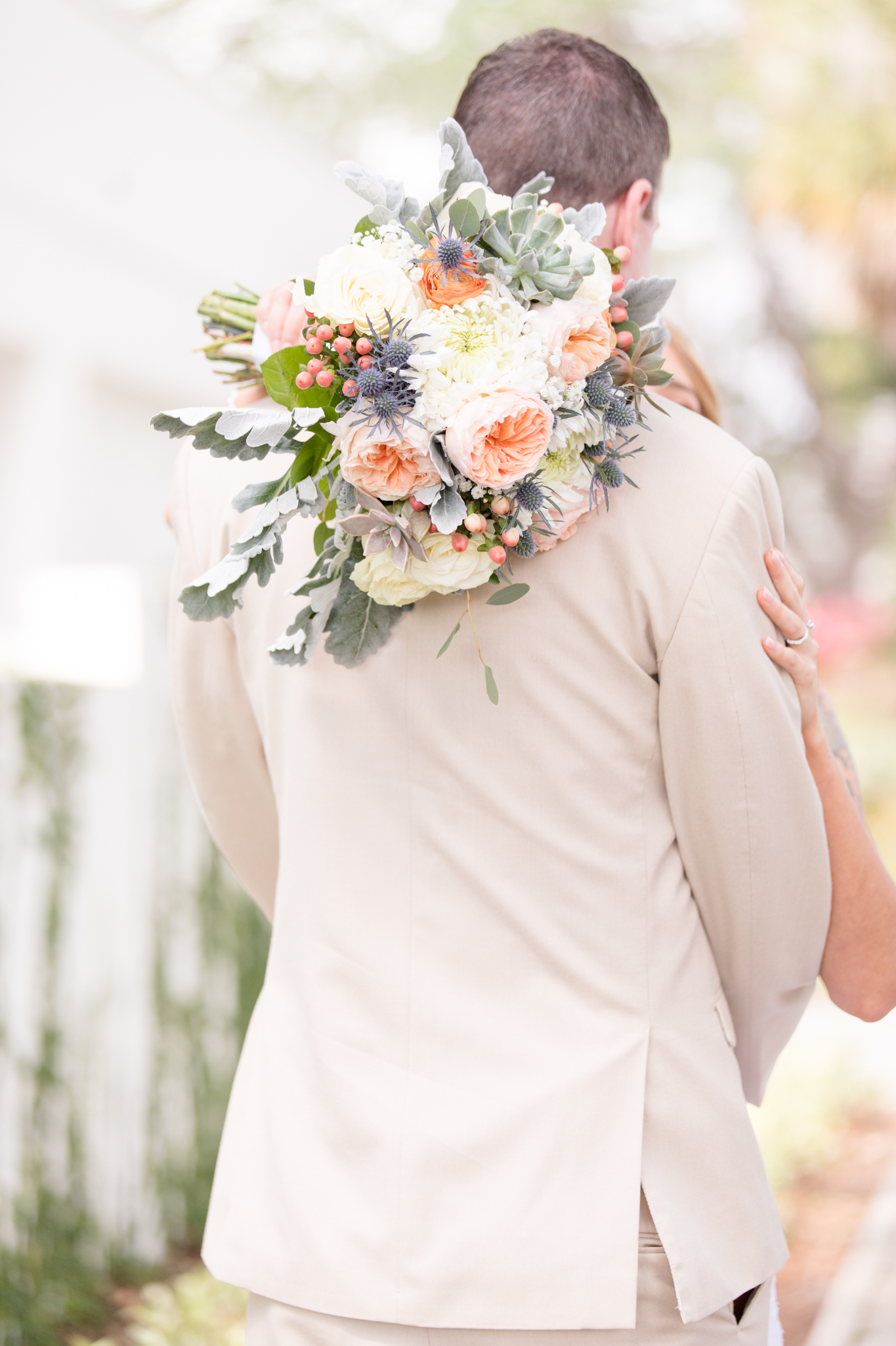 Bridal bouquet overe groom's shoulder.