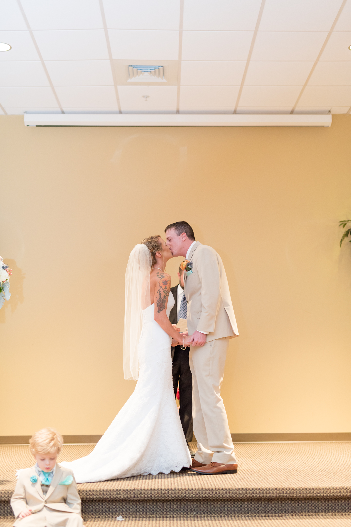Bride and groom kiss during wedding ceremony.