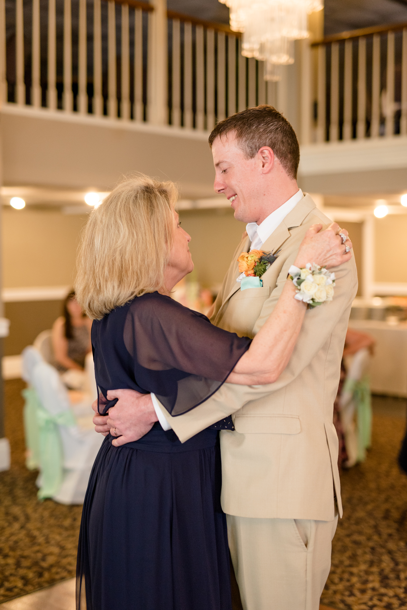 Groom dances with mother at wedding reception.