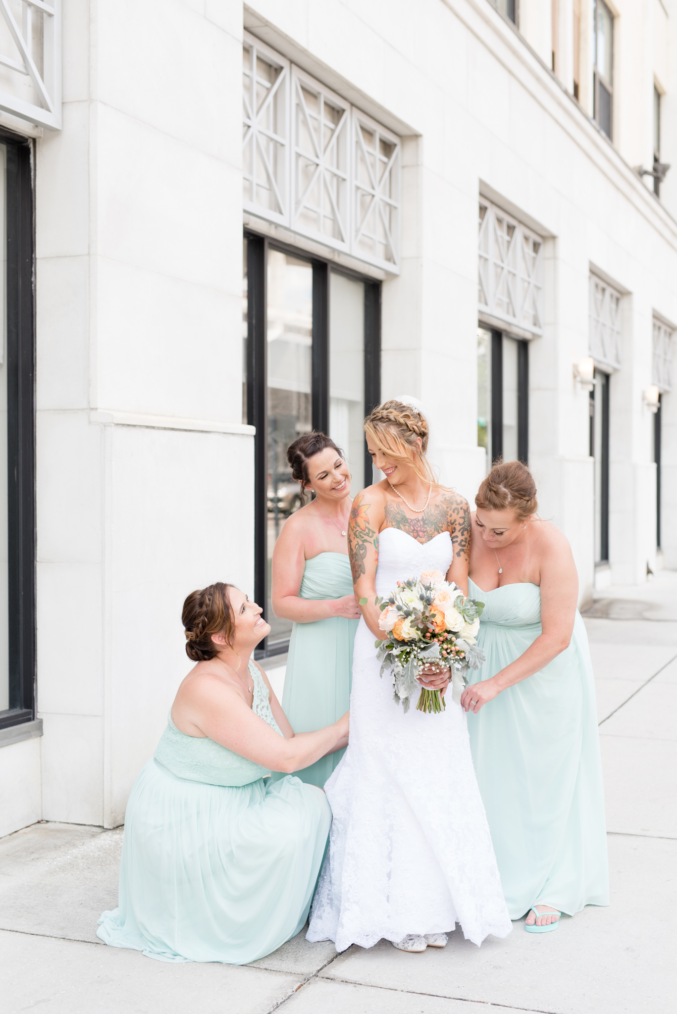 Bridal party helps bride straighten dress.