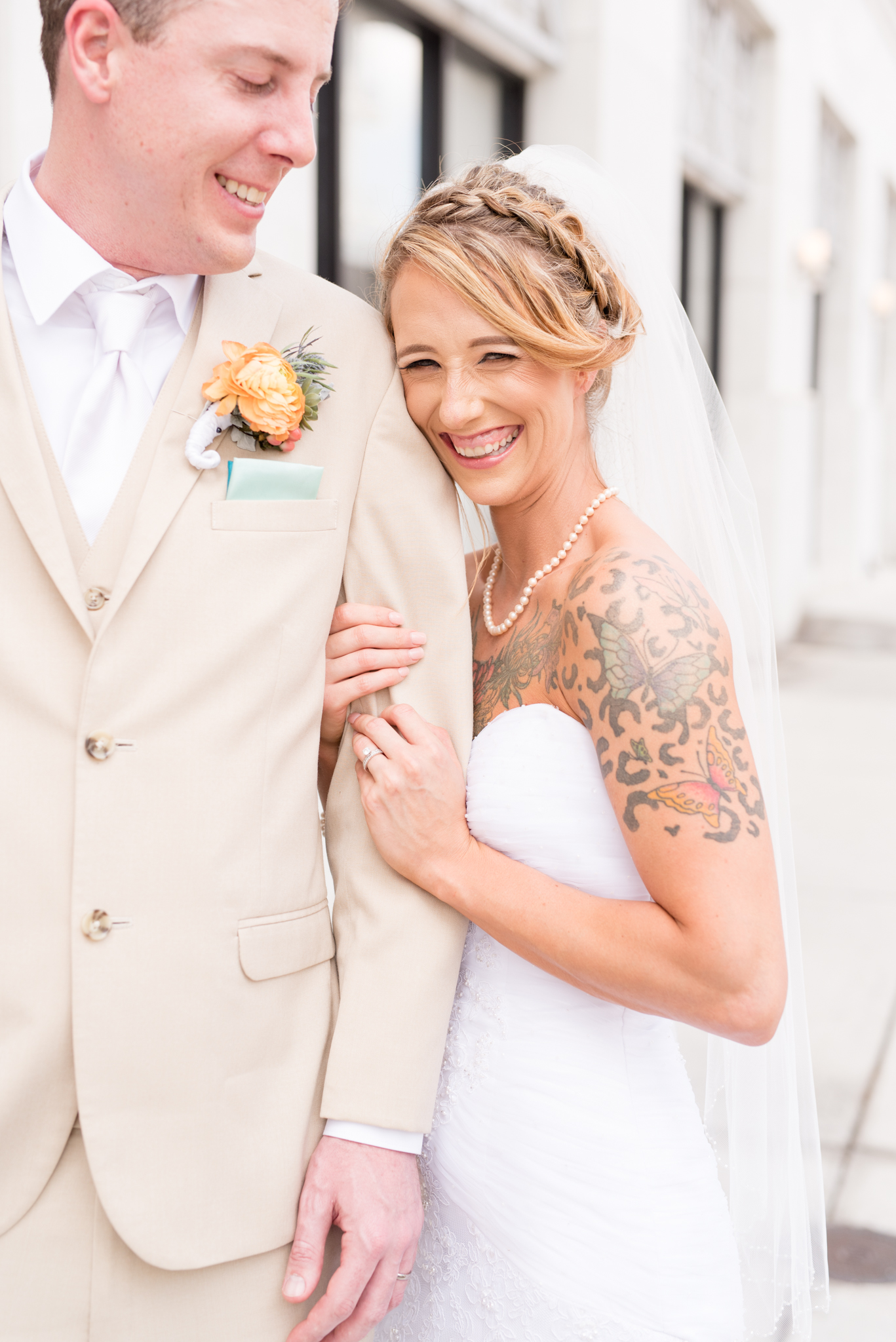 Bride laughs as she holds onto groom's arm.