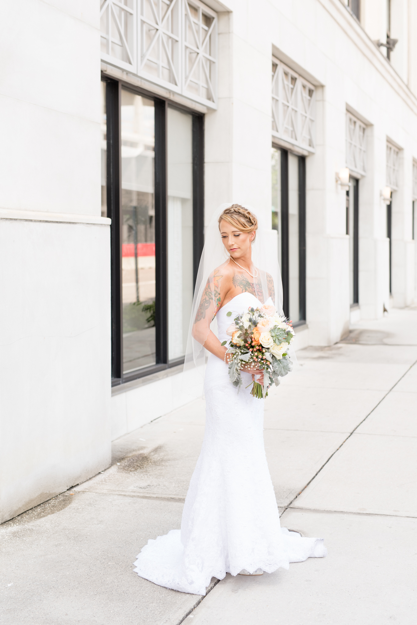 Bride looks over shoulder on sidewalk.