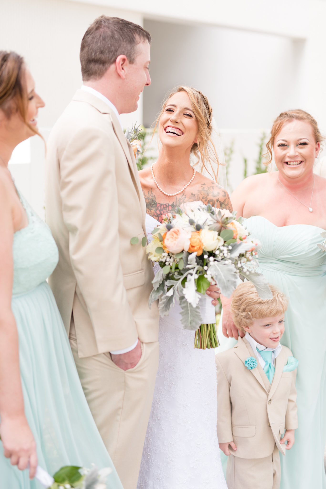Bride laughs with groom and wedding party.