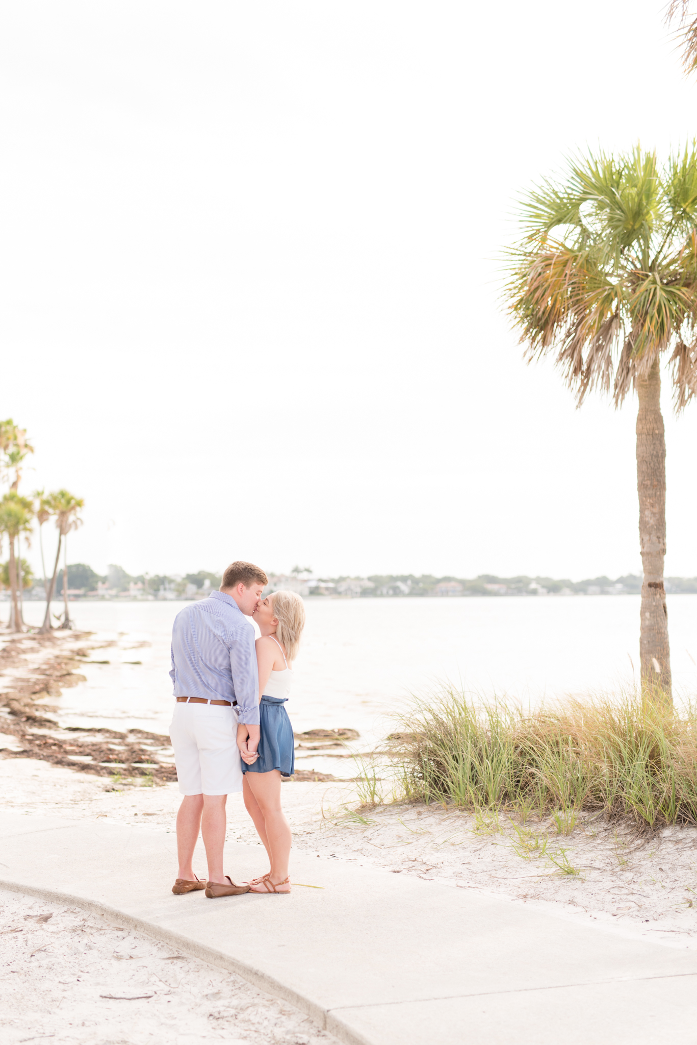 Couple kisses on beach boardwalk.