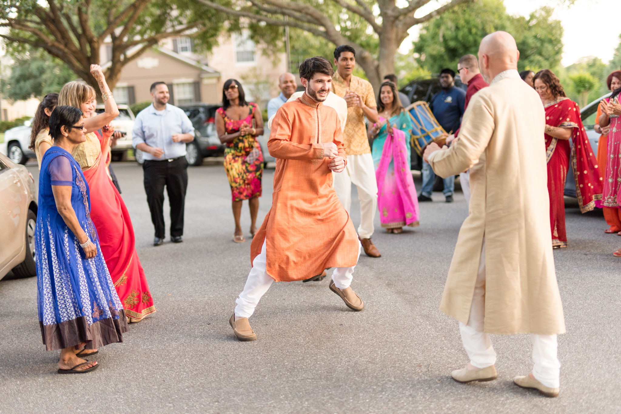Wedding guests dance in street.