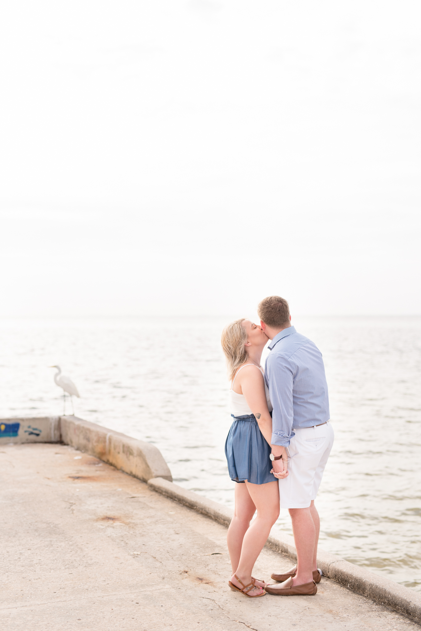 Woman kisses boyfriend on pier.