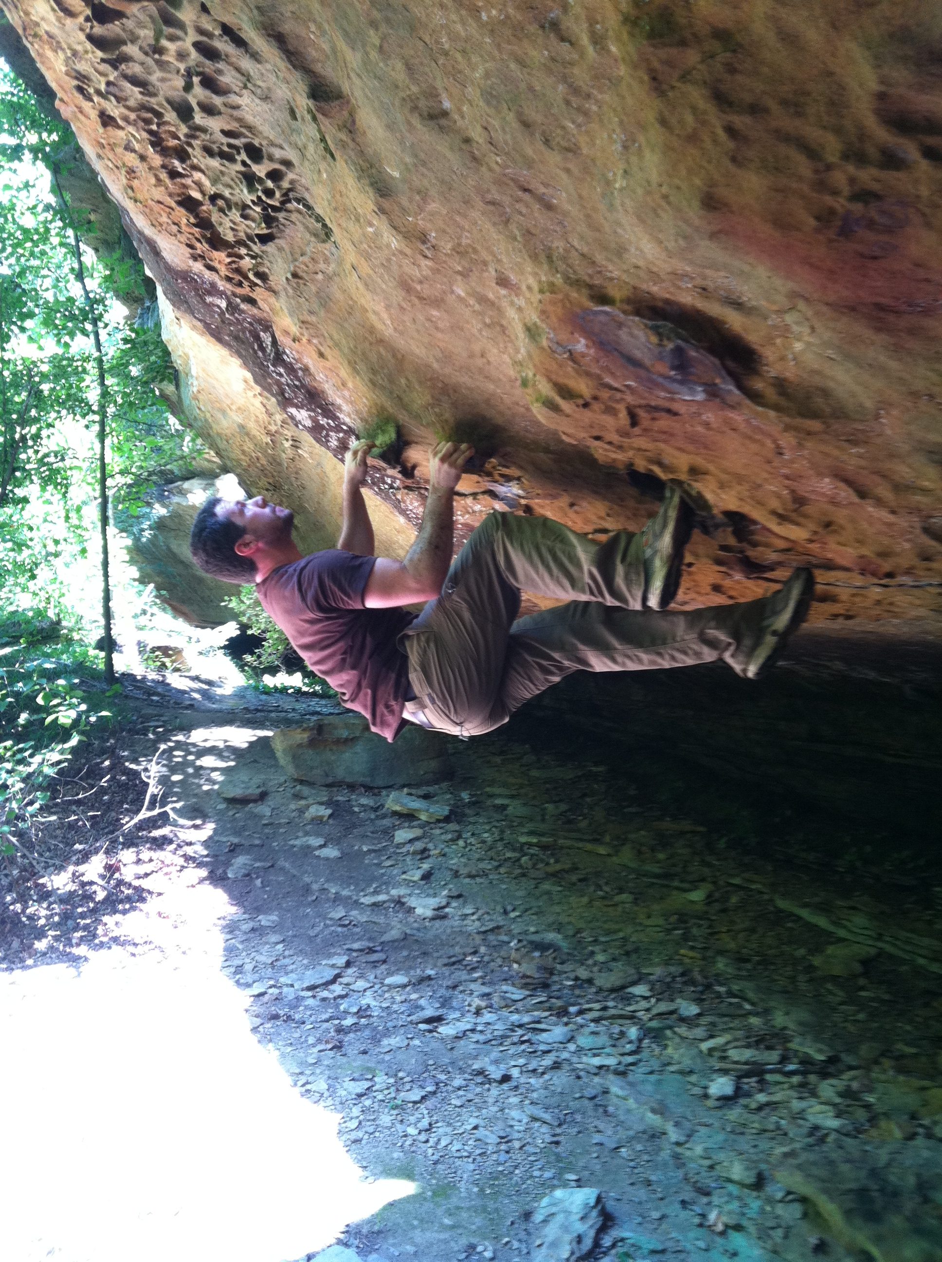 man hangs upside down while rock climbing.